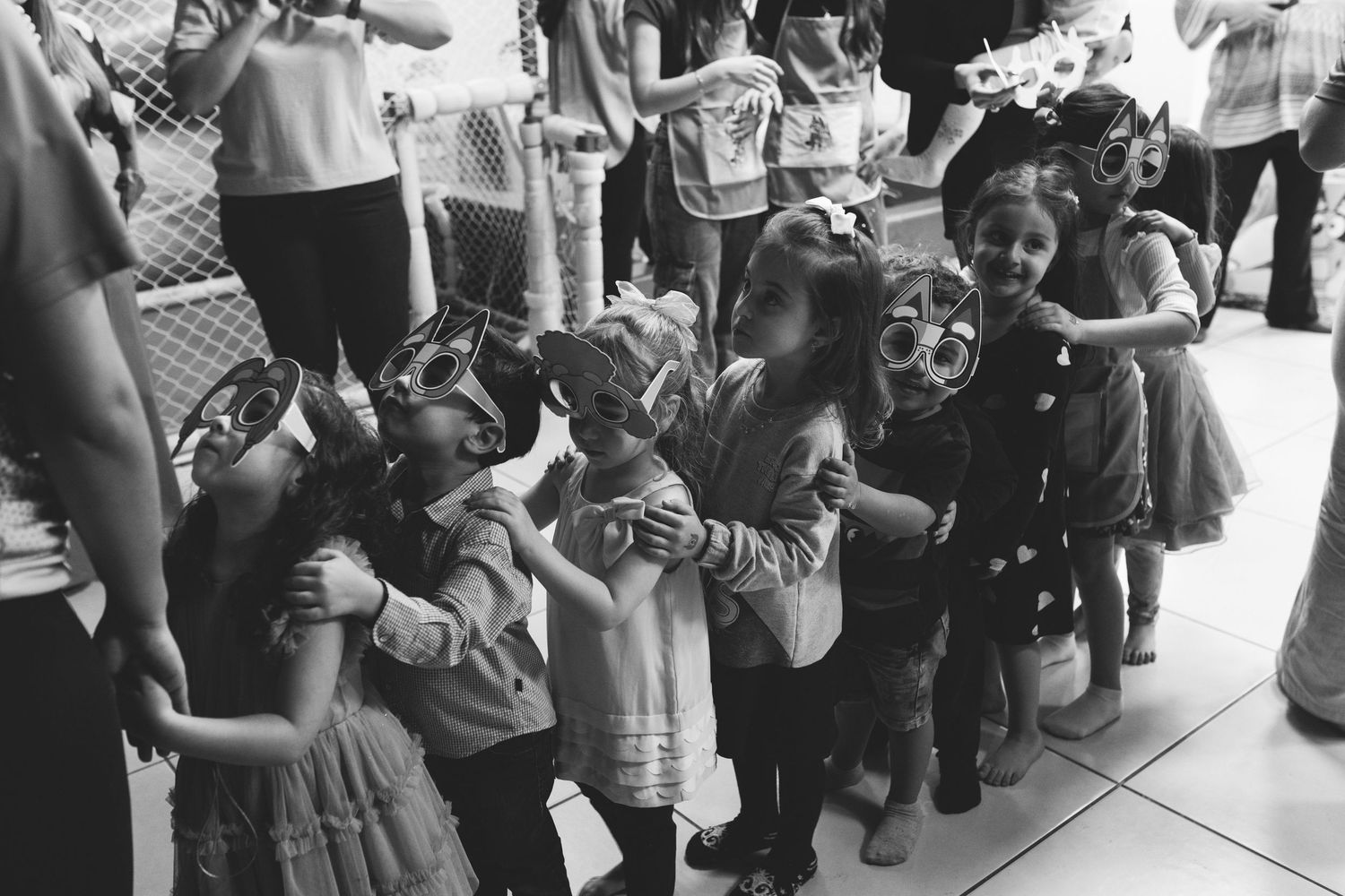 Black and white photo of young children in costume masks gathered together at a festive kids party.