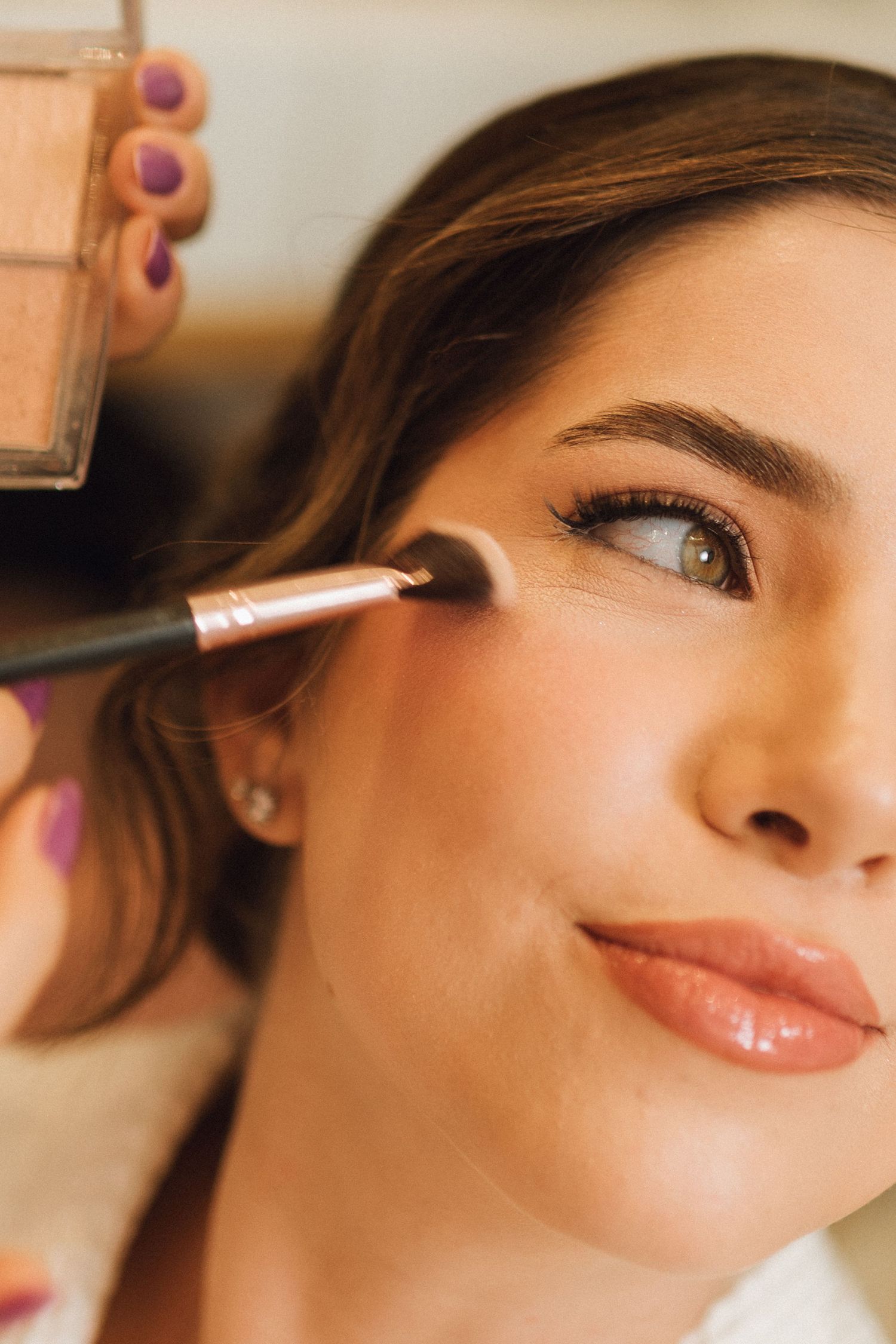 Professional makeup artist applying eyeshadow to a beautiful bride before her wedding.