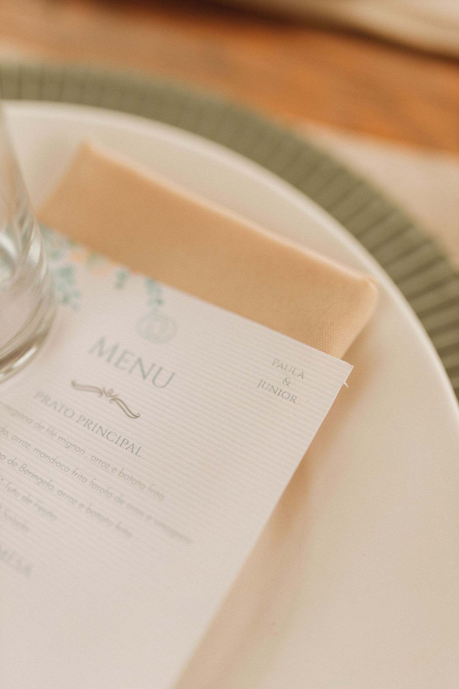 Elegant wedding menu card on white plate with sage green rim, personalized for Zaiga and Junior.