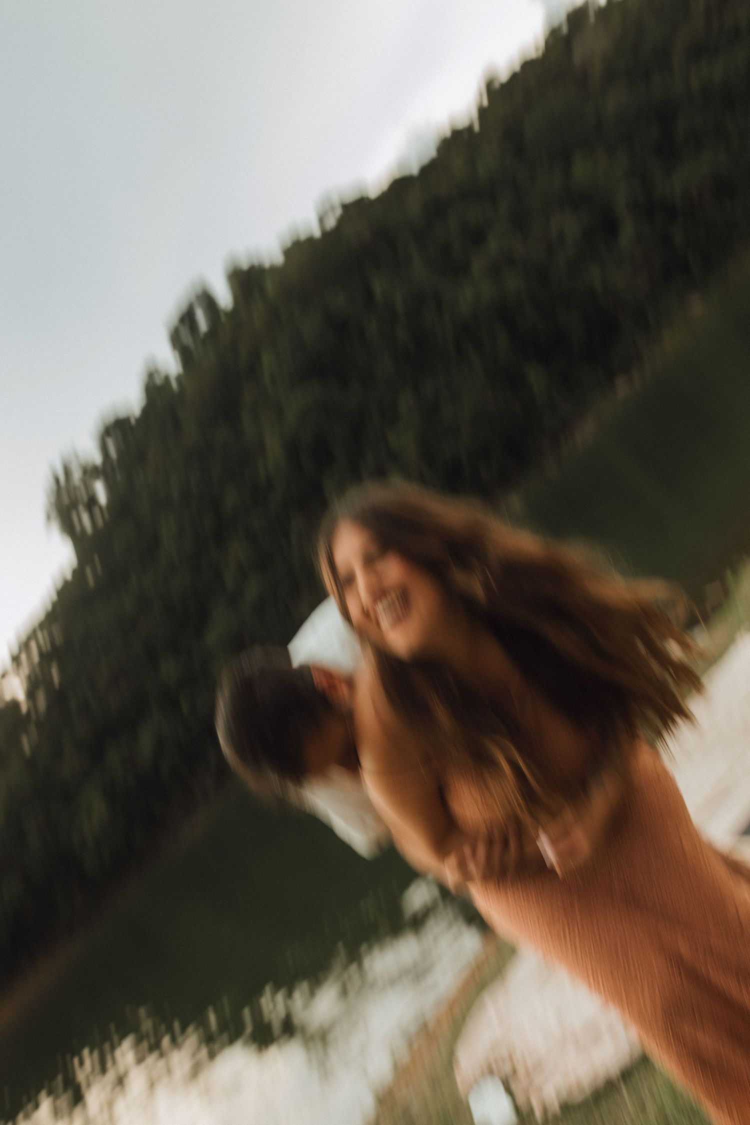 Blurred motion photo of smiling woman in orange dress outdoors.