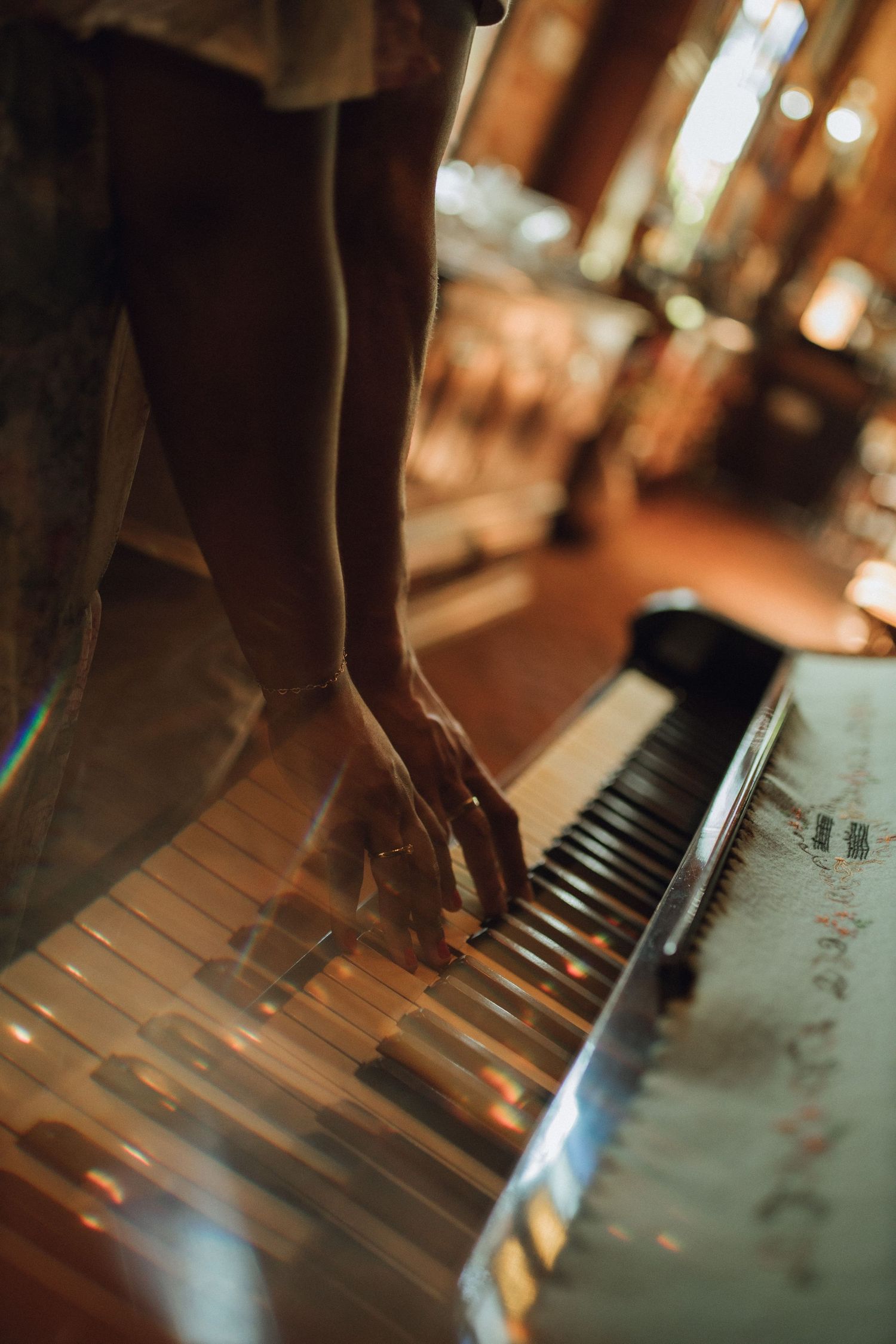 Close-up of hands playing an antique piano keys in warm golden light.