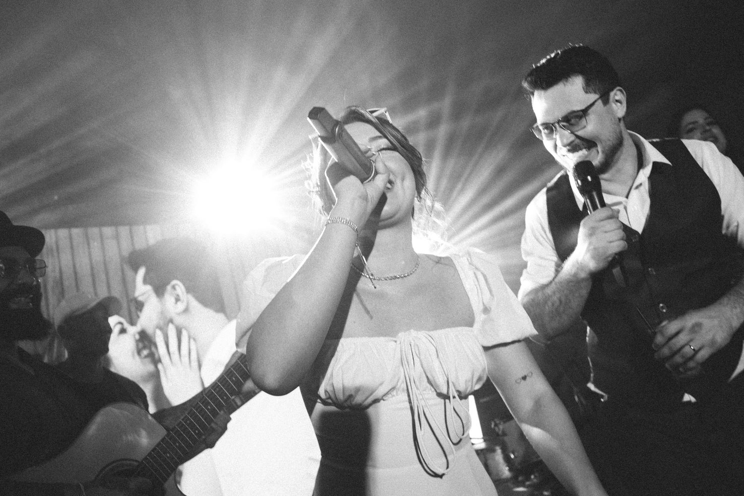Black and white photo of energetic wedding reception performance with singer and excited crowd.