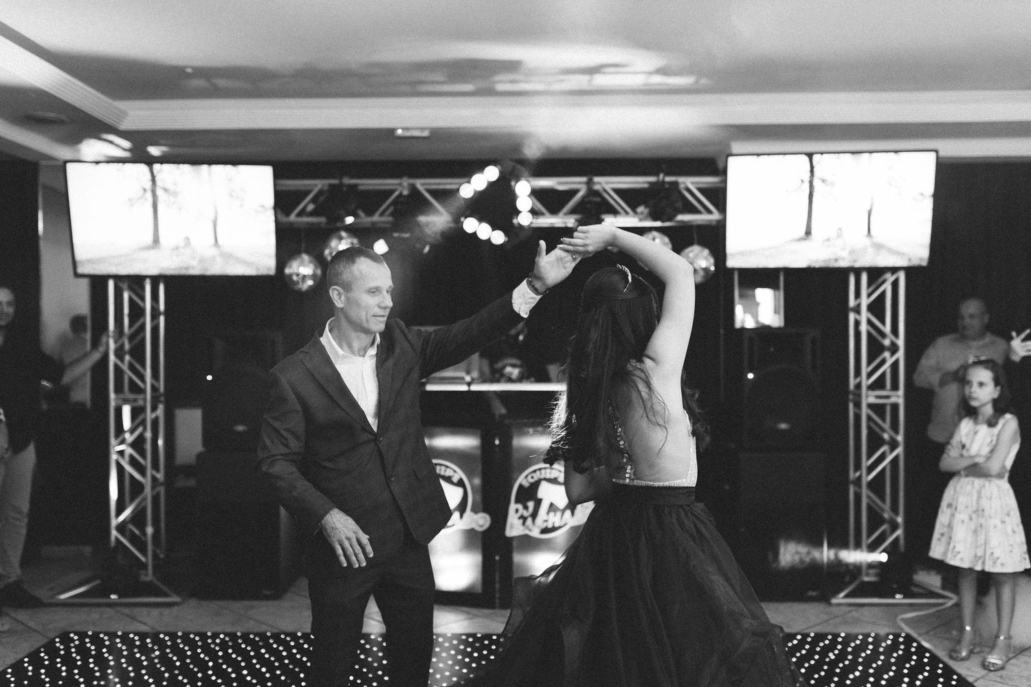 Couple dancing at formal event with fire performance on black dance floor in black and white photo.
