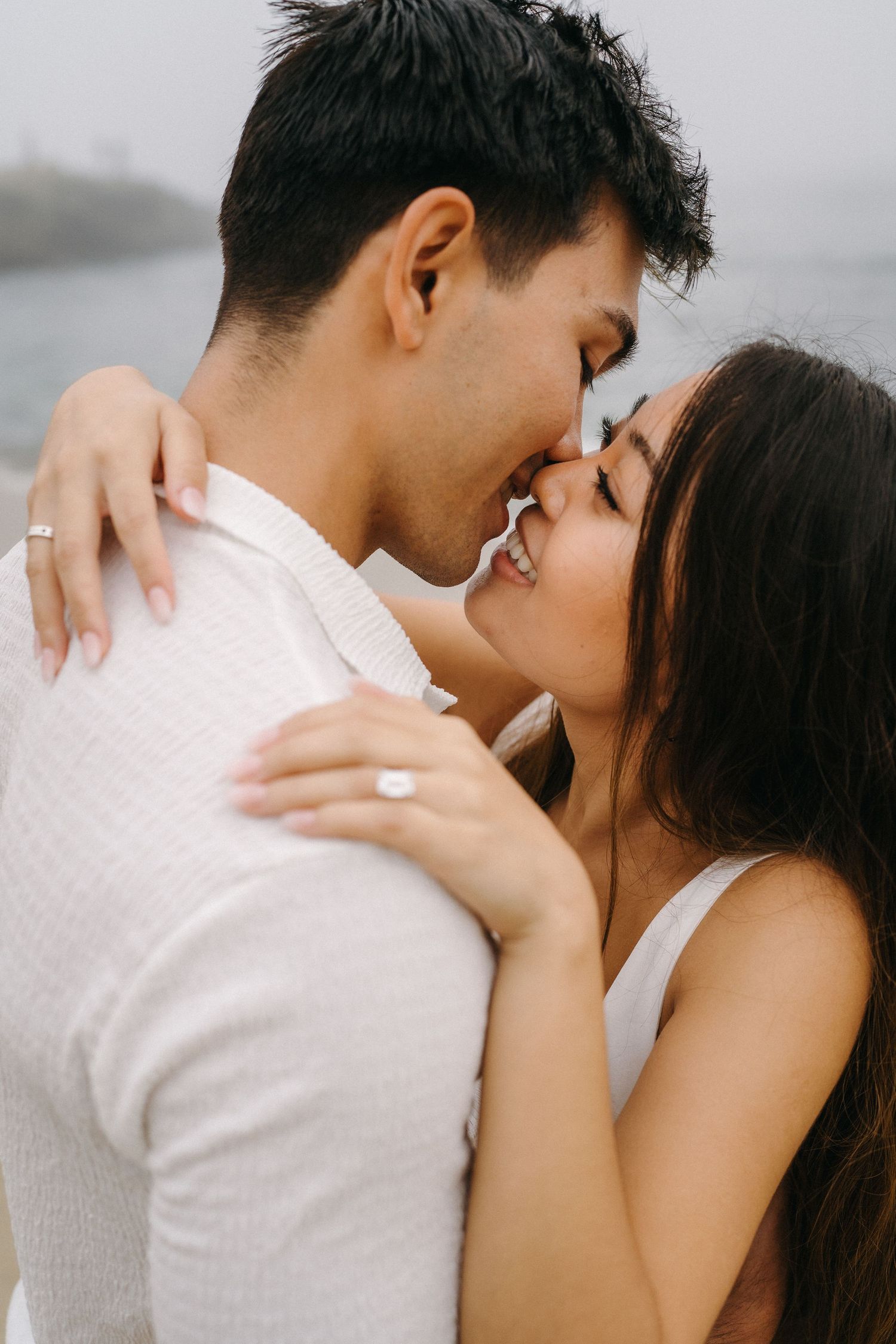Close up image of a couple sharing a kiss at Laguna Beach with the ocean in the background during an engagement photography session.