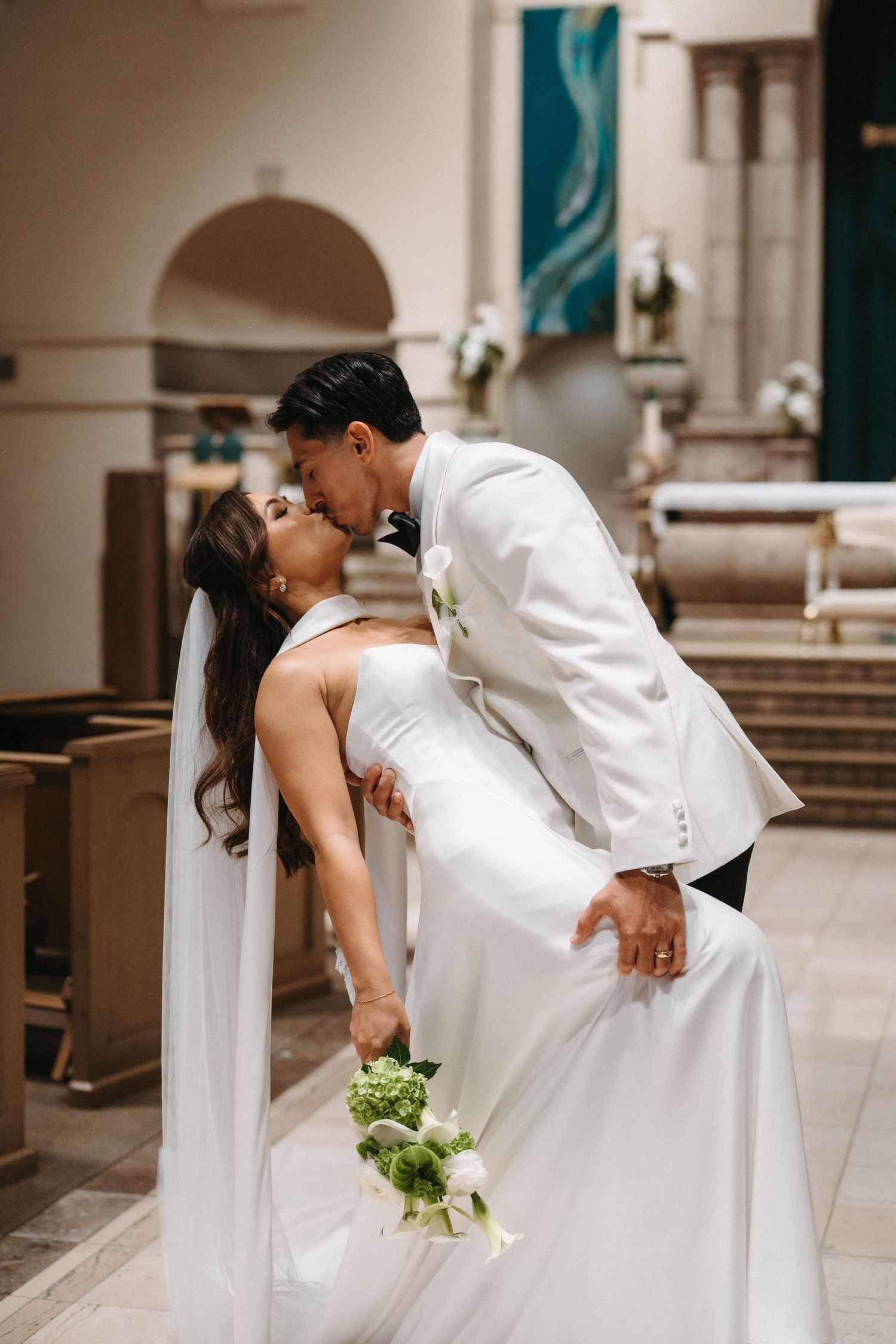 Newlyweds kissing as they walk up the aisle after their church wedding ceremony.
