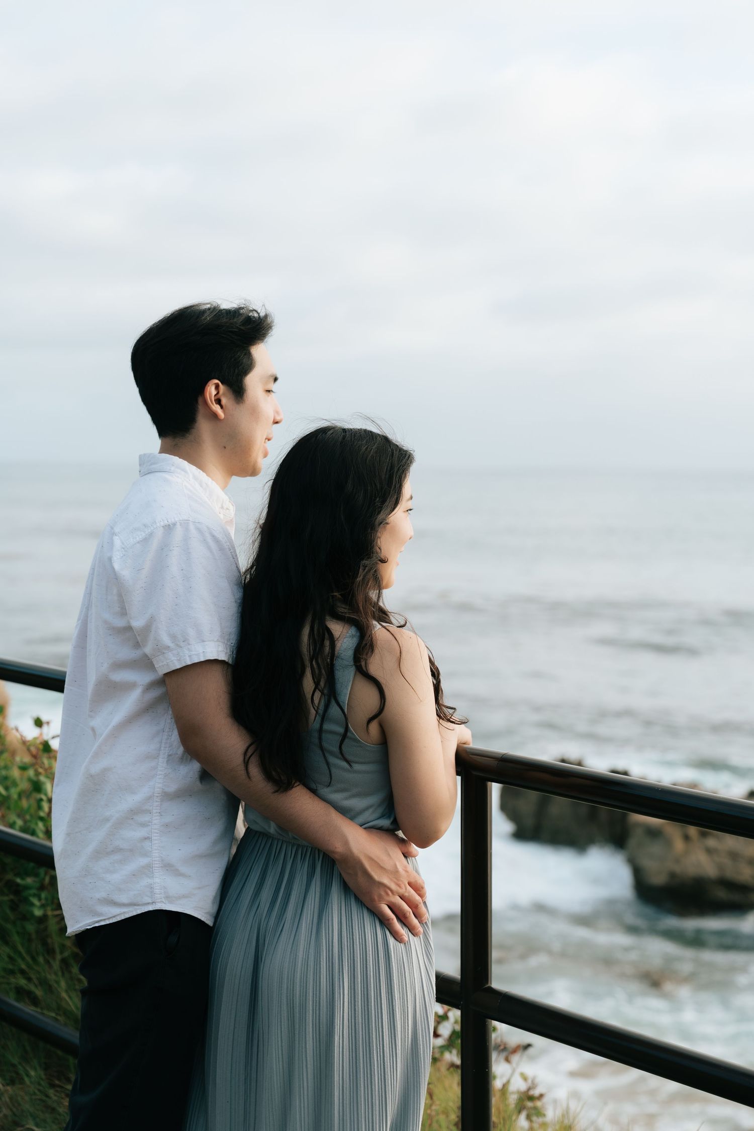 Back view of newly engaged couple looking out into the ocean in Laguna Beach.