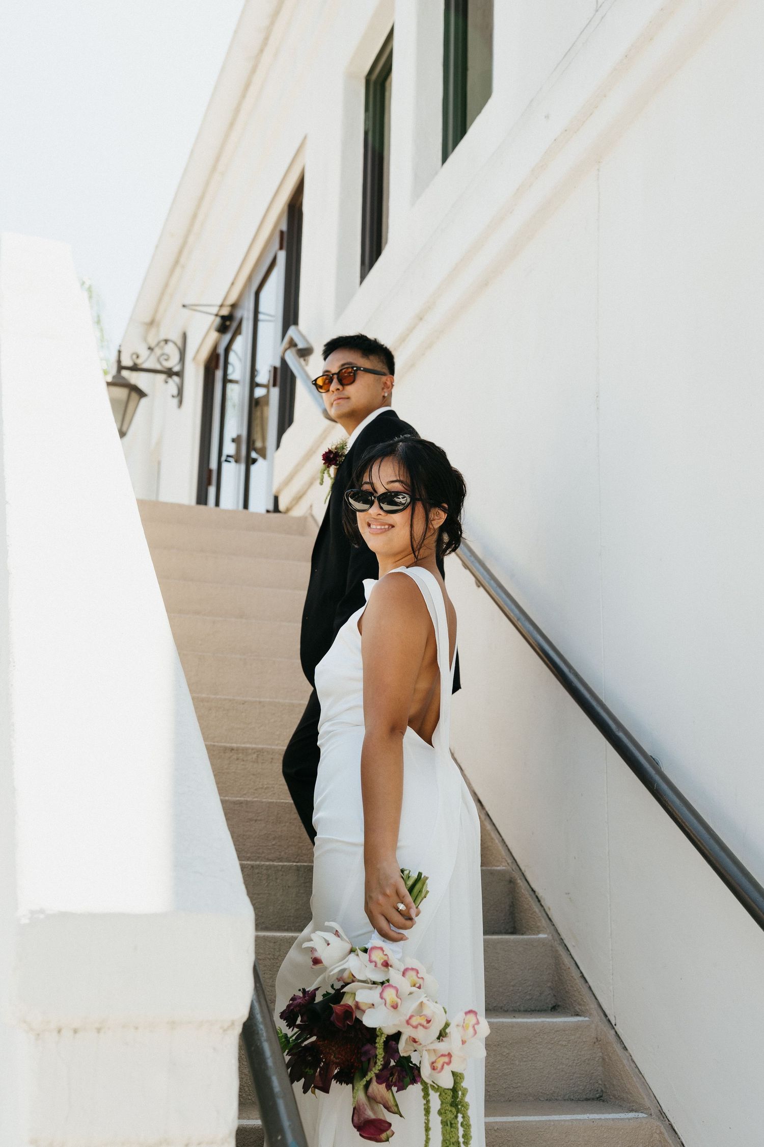 Bride and groom walking hand in hand up stairs during elopement.