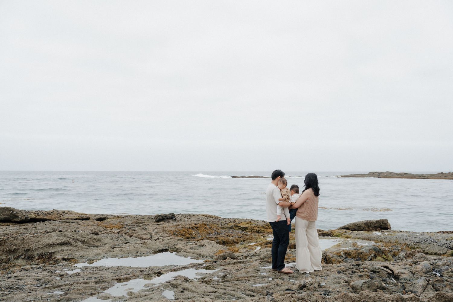 Candid family photos standing on the rocks at Laguna Beach.