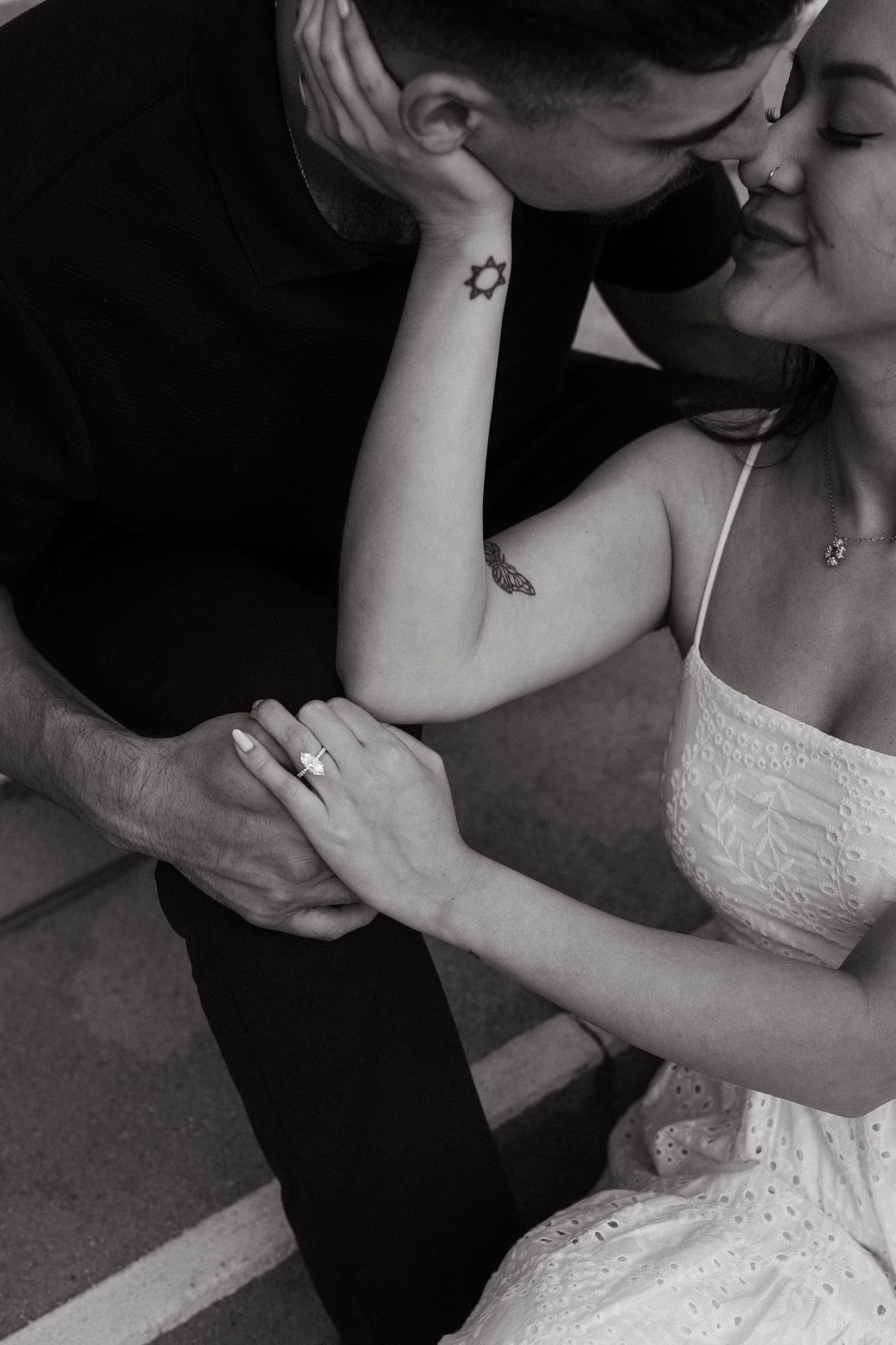 Black and white photo of a couple sharing a kiss outside of Pasadena City Hall, woman wearing engagement ring.