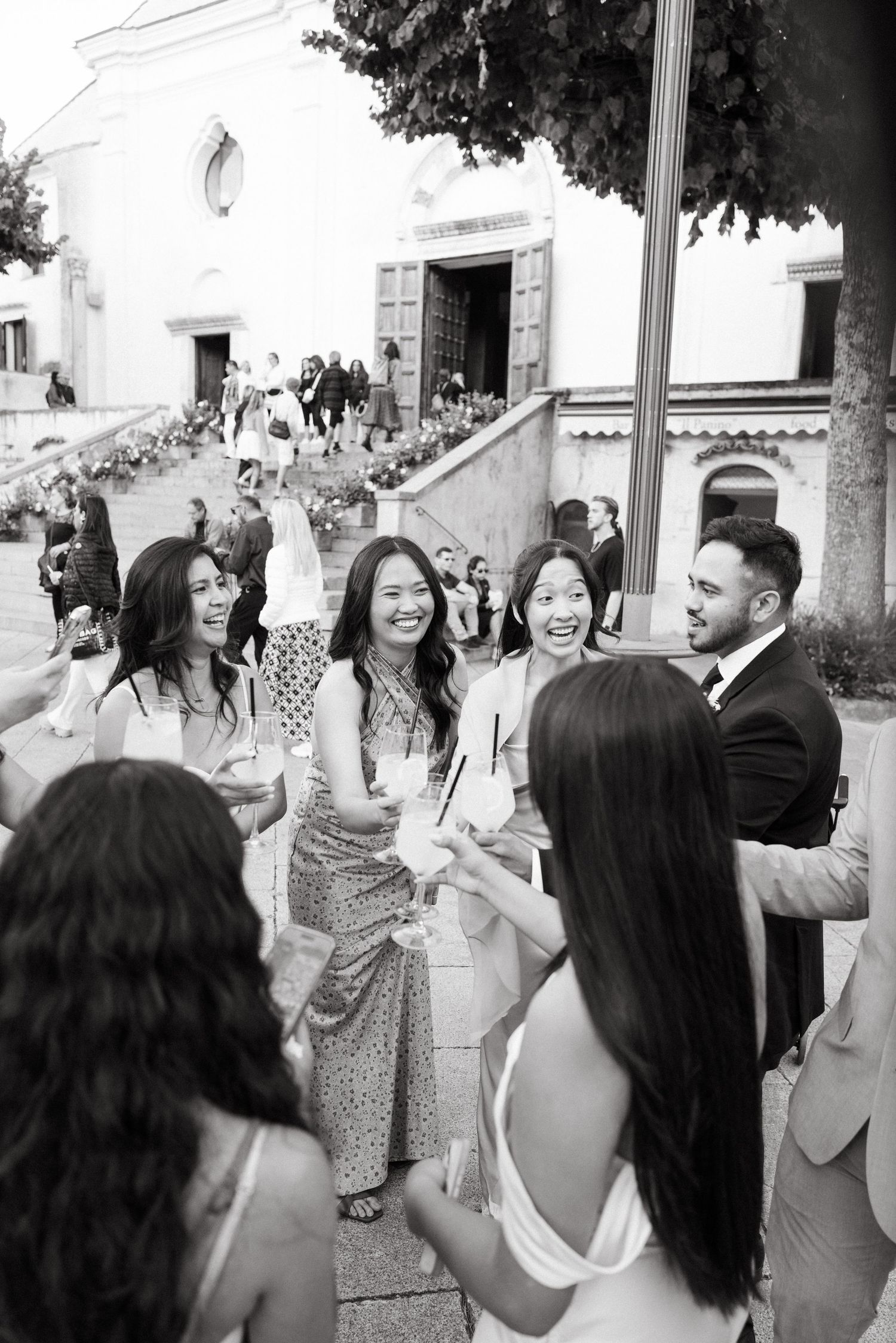 Wedding guests clinking glasses during cocktail hour in black and white.