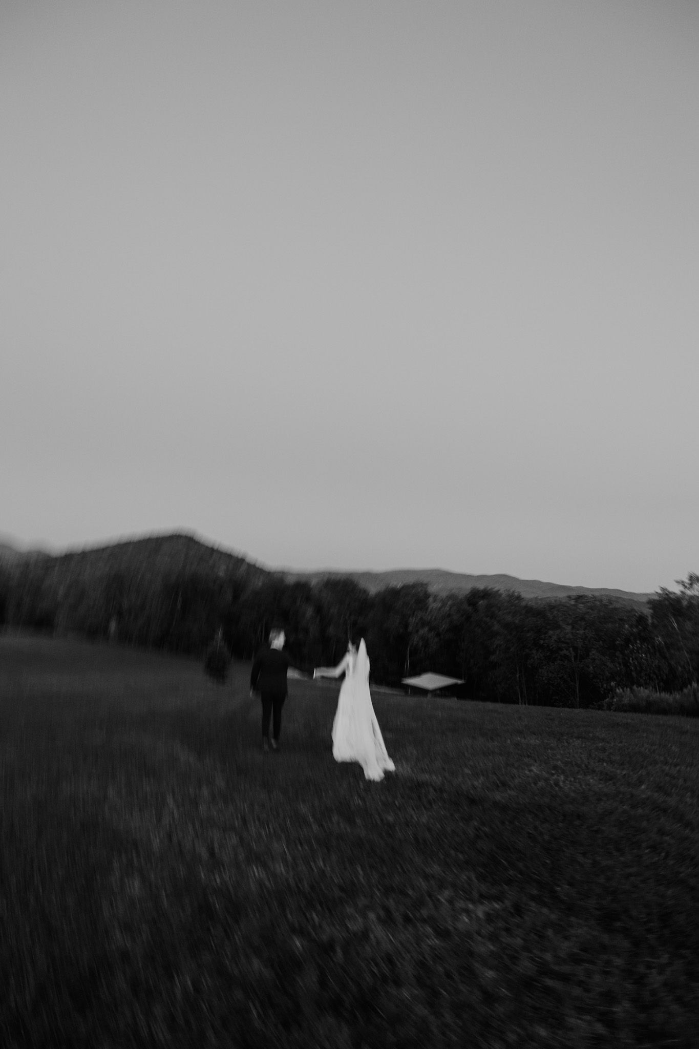 A bride and groom stand on a porch surrounded by wedding guests.
