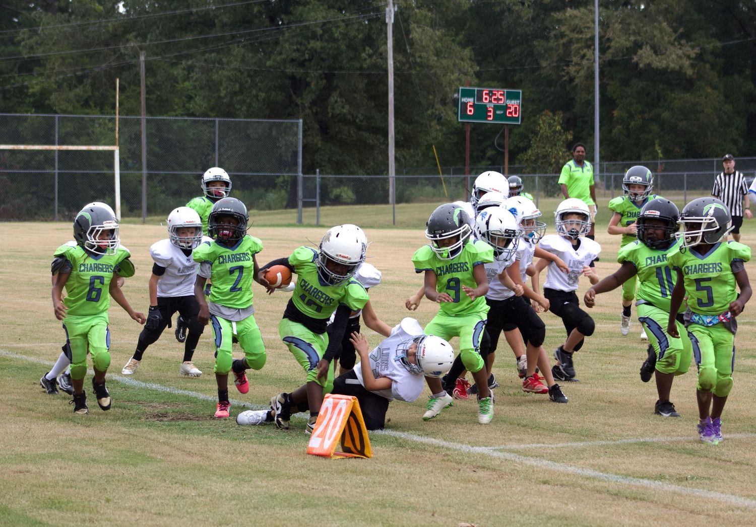 Little league travel football player pushing down his opponent to avoid being tackled with the ball.
