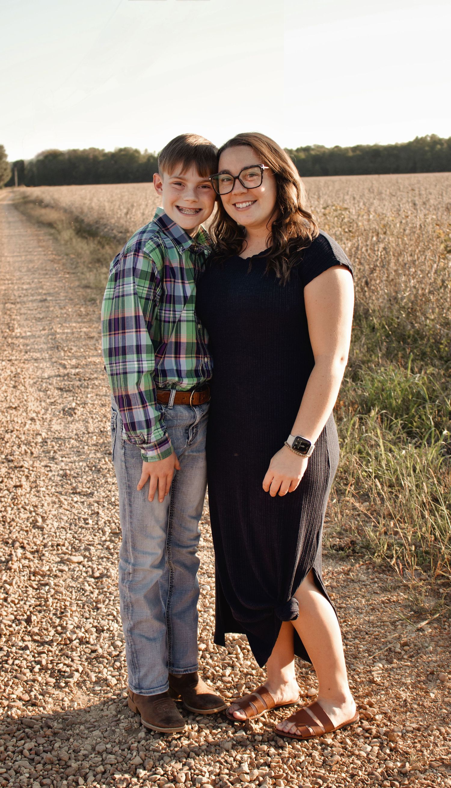 Mother and son standing for a portrait style photo on a dirt road.