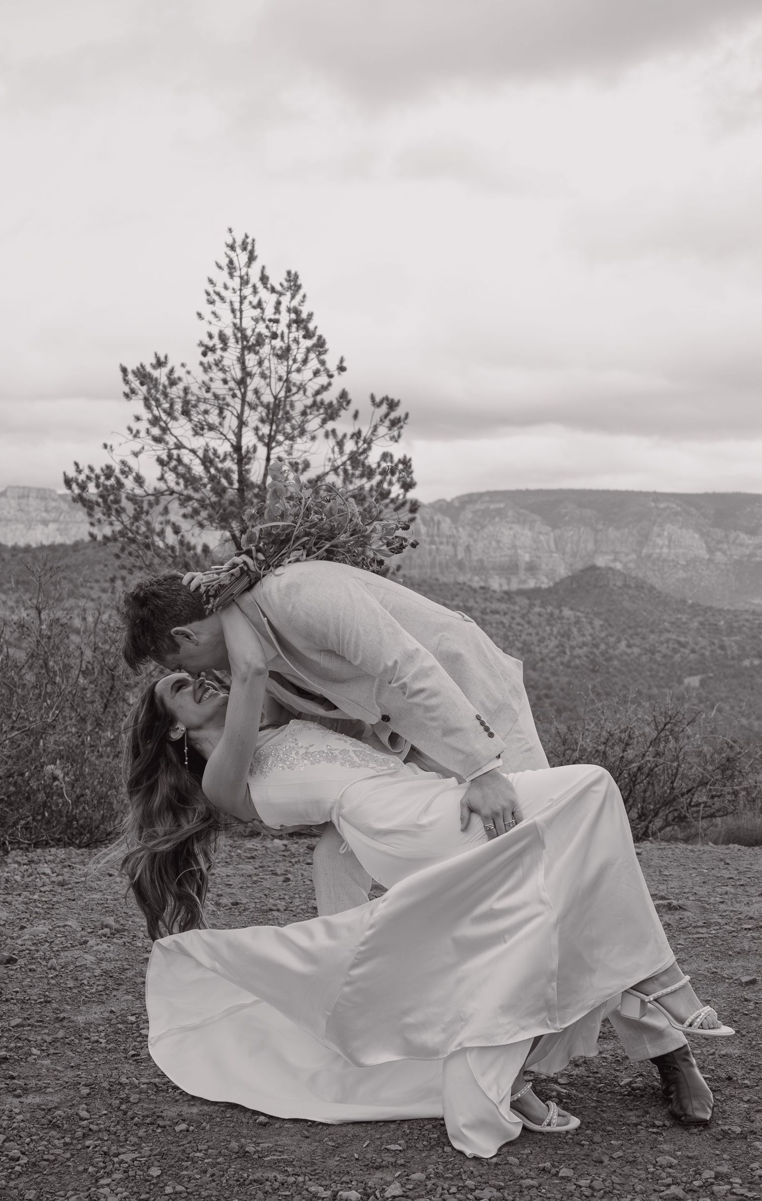 Black and white dramatic dip kiss between bride and groom with canyon backdrop.