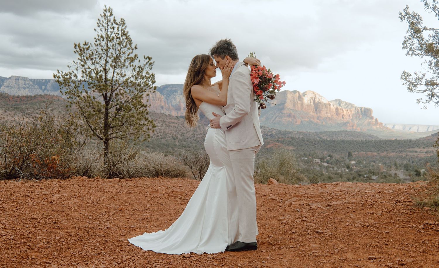 Couple sharing romantic kiss at red rock Sedona Arizona wedding ceremony outdoors.