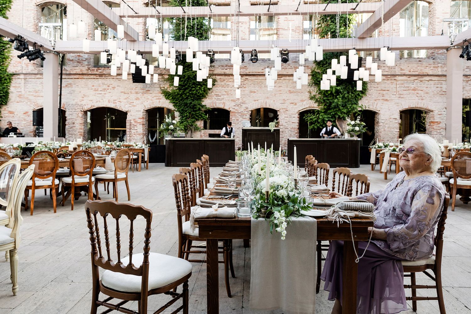 An elegant outdoor wedding reception setup at Esma Sultan in Istanbul, featuring long wooden tables, floral runners, and hanging lights.