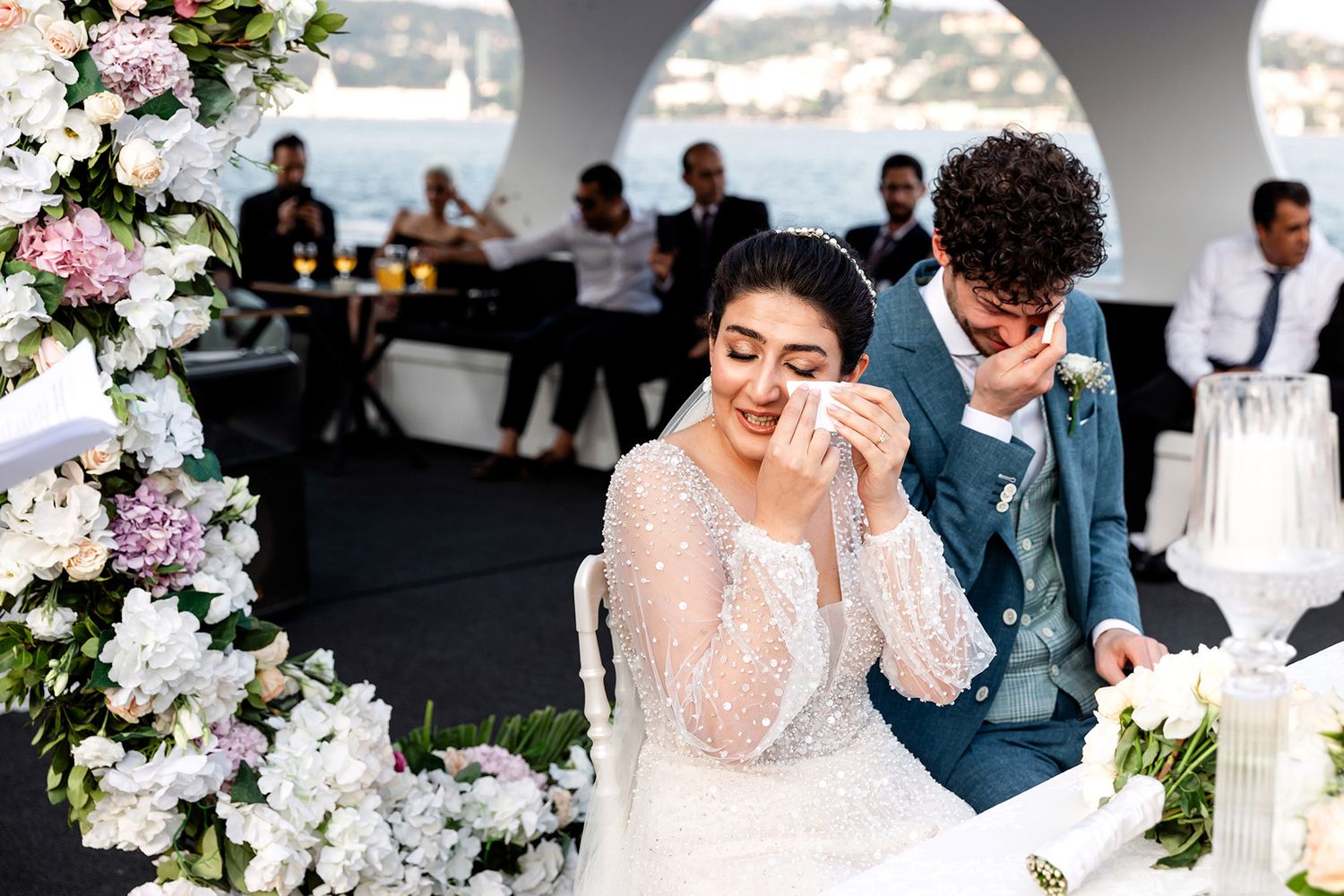 A bride and groom wipe away tears during their, intimate German-Iranian wedding ceremony on a boat cruising the Bosphorus in Istanbul.