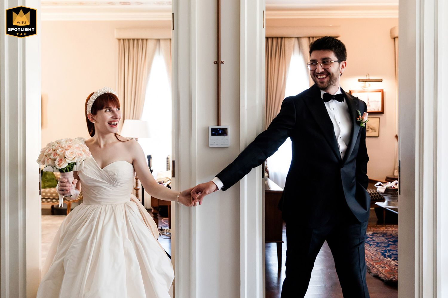 WPJA award-winning candid photo of a laughing bride playfully pulling her groom by the hand through double doors at an Istanbul wedding.