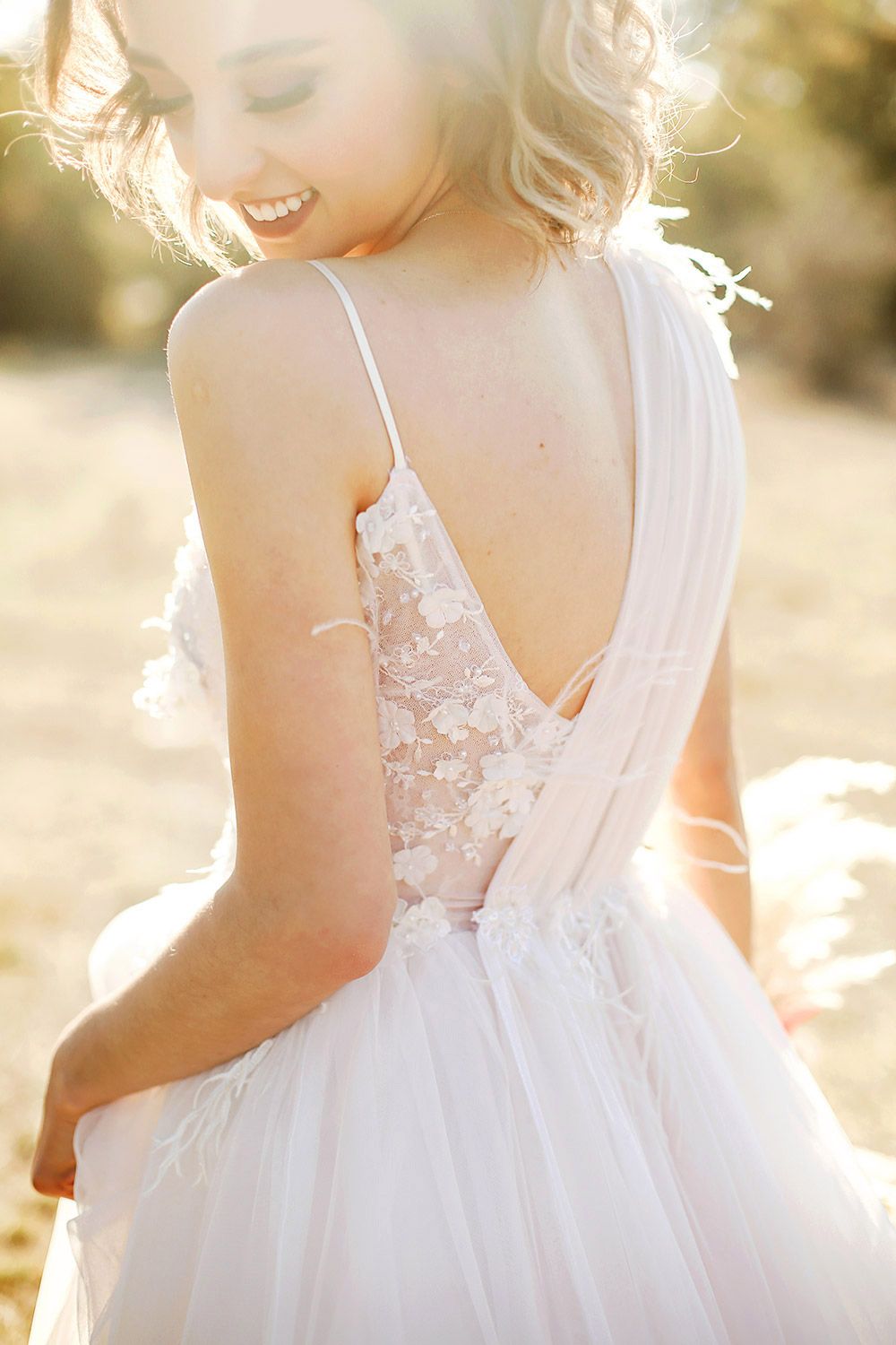 A candid, bridal portrait taken during golden hour in Bursa, smiling bride in a  lace and feather wedding dress looking over her shoulder.