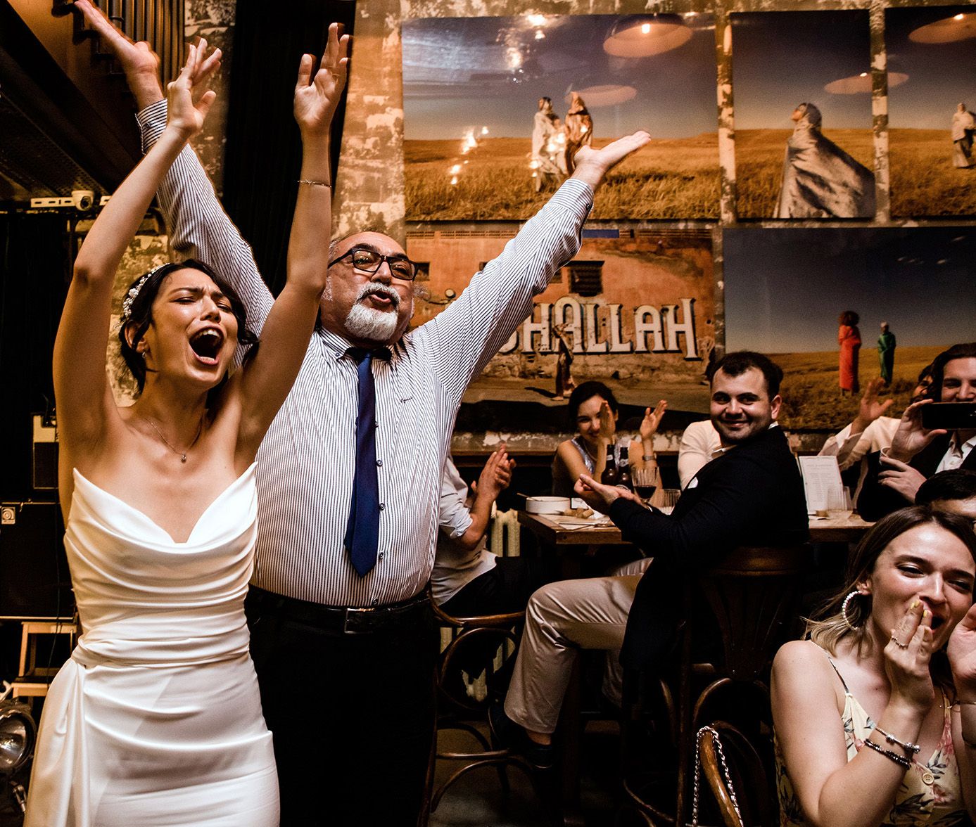 Photo of a bride and guest cheering joyfully with raised arms during an energetic Istanbul wedding reception.