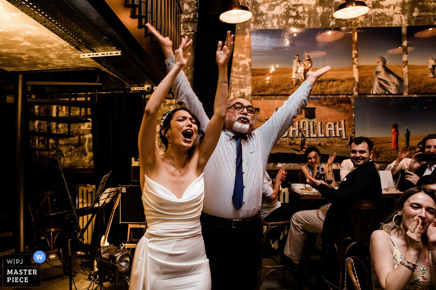 WPJA award-winning candid photo of a bride and guest cheering joyfully with raised arms during an energetic Istanbul wedding reception.