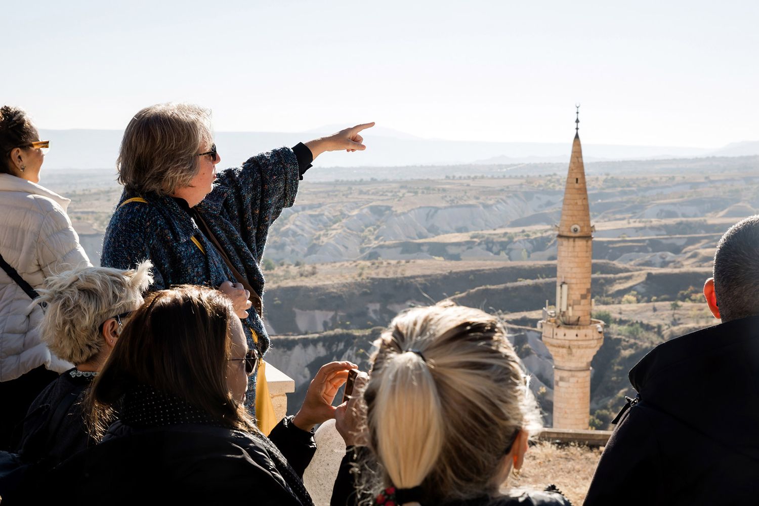 A tour guide pointing out historic landmarks to a corporate group during a scenic destination retreat in Cappadocia.