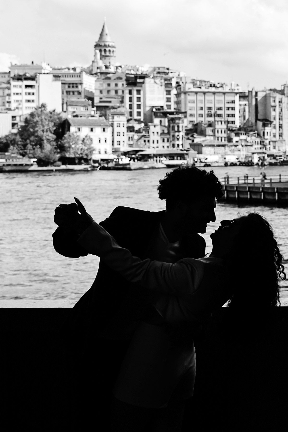 A black and white silhouette of a couple joyfully dancing and dipping against the iconic backdrop of the Galata Tower.