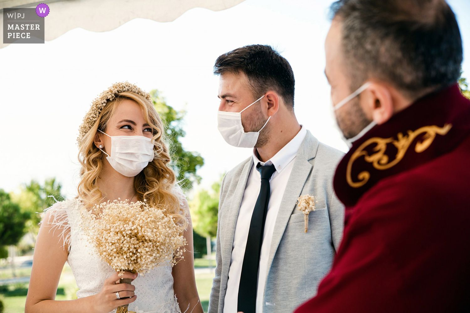 WPJA Masterpiece award-winning candid photo of a smiling bride and groom wearing masks during their unscripted wedding ceremony.