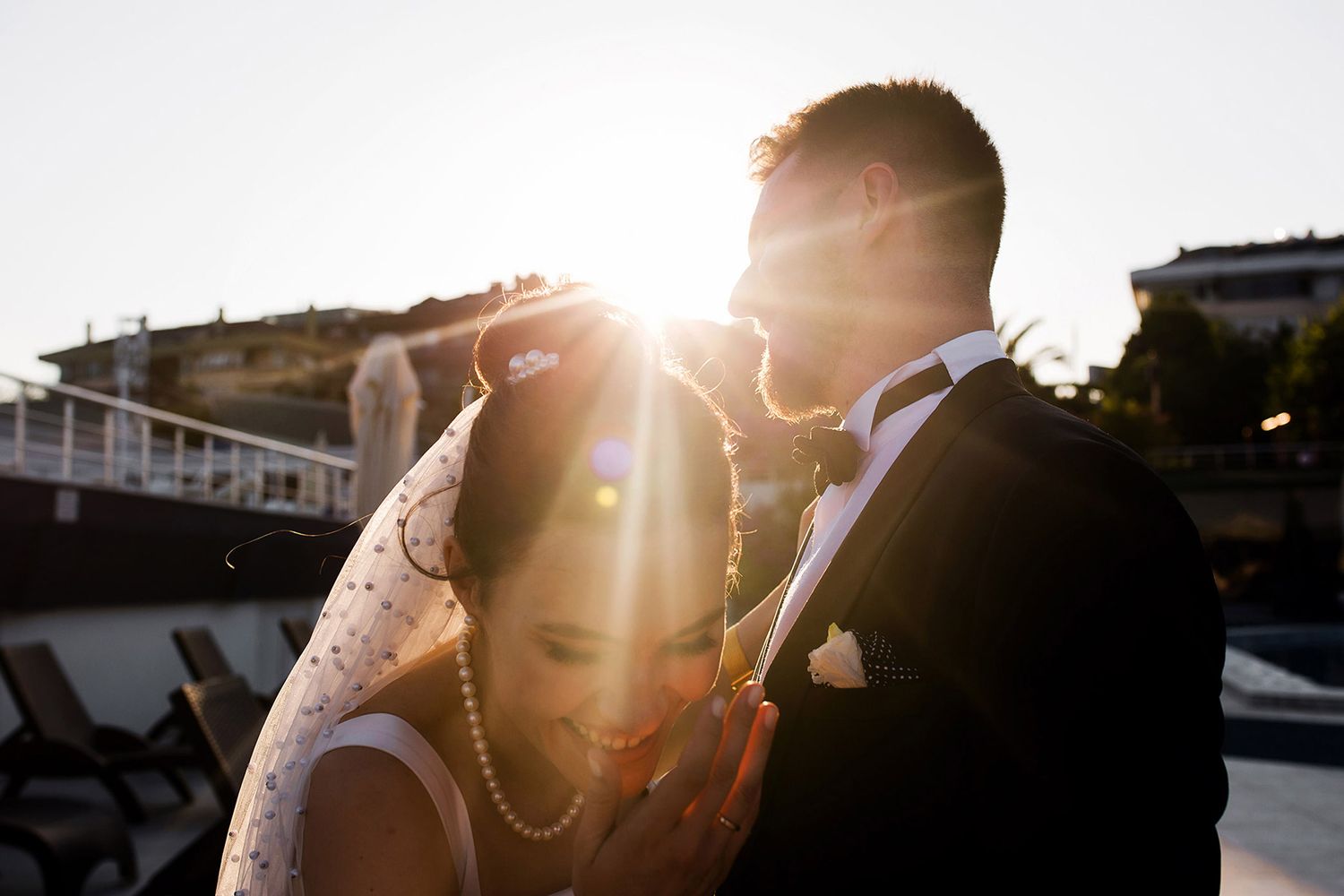 Candid golden hour portrait featuring a brilliant sun flare as a bride laughs genuinely with her groom during a Florya wedding.