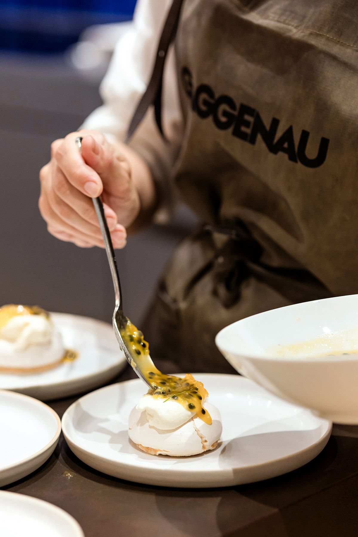Close-up of a chef in a Gaggenau apron carefully plating a passion fruit dessert during a high-end corporate dining event in Istanbul.