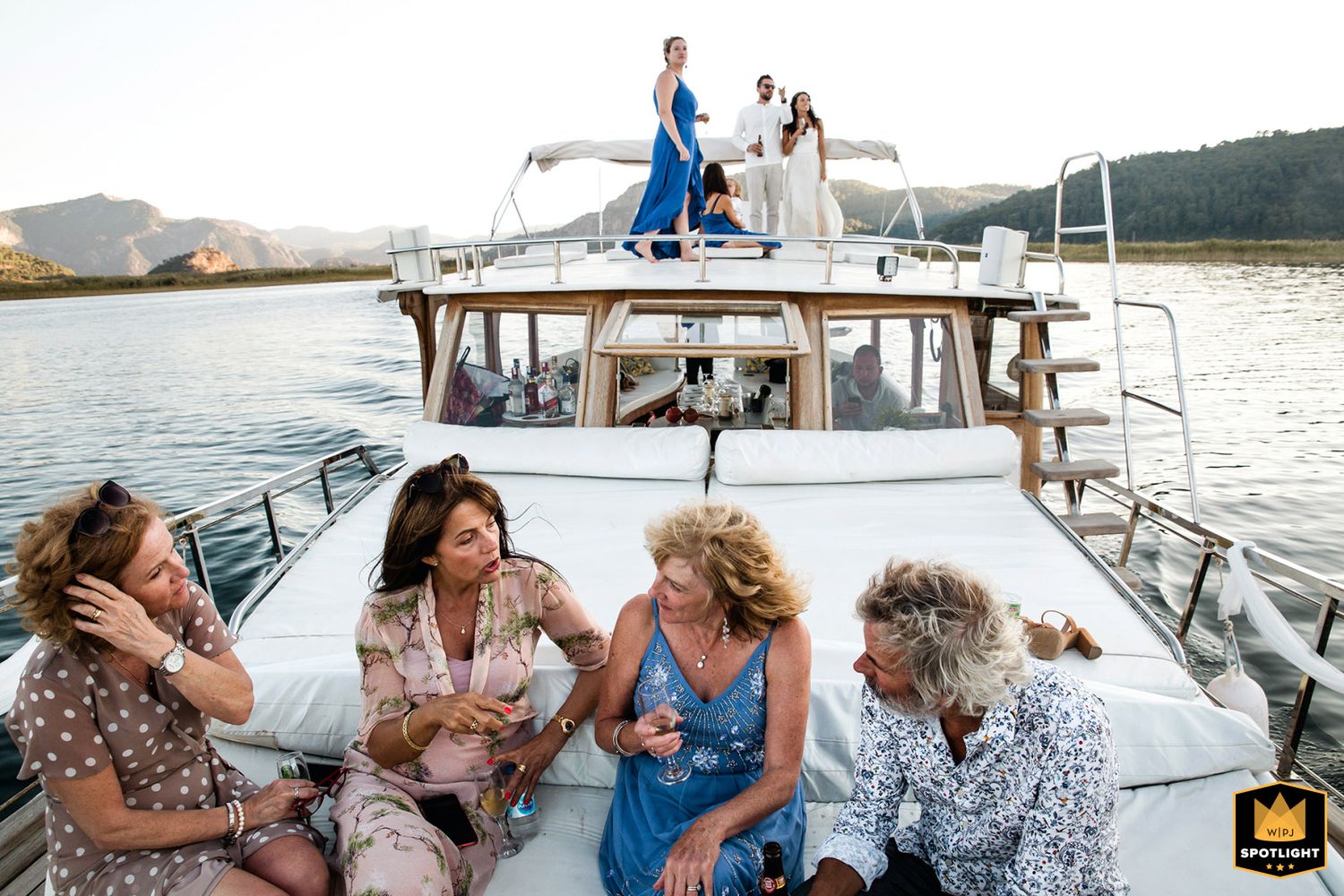WPJA award-winning documentary photo of wedding guests relaxing and chatting on the deck of a boat during a destination wedding.