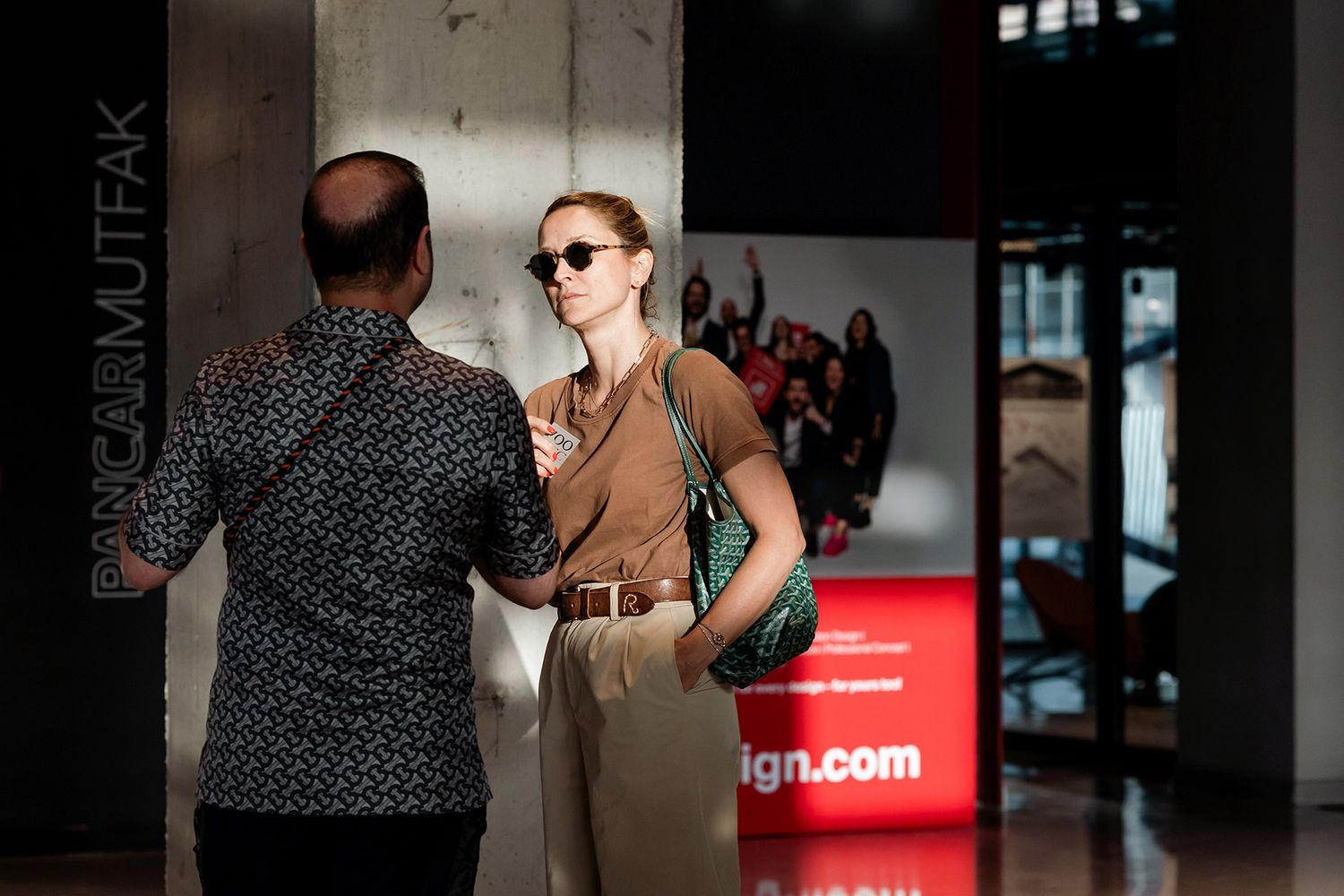 A female corporate executive wearing stylish sunglasses engaged in a candid networking conversation at the iF Design Award event.