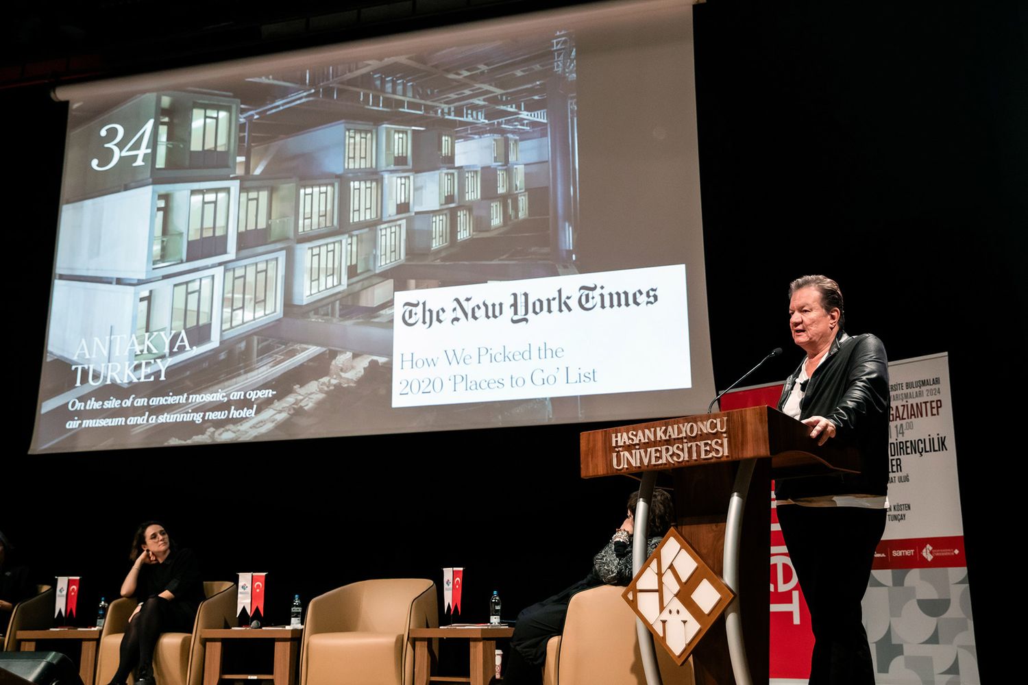 A male keynote speaker delivering a presentation on stage at a Hasan Kalyoncu University corporate event.