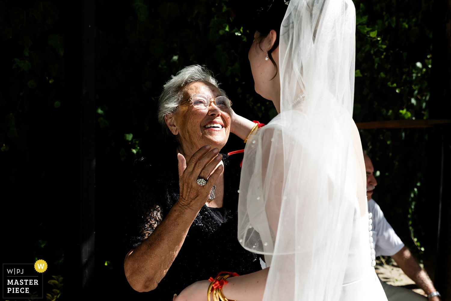 WPJA award-winning documentary photo of a grandmother looking proudly at her granddaughter in her wedding dress, gently touching her face.