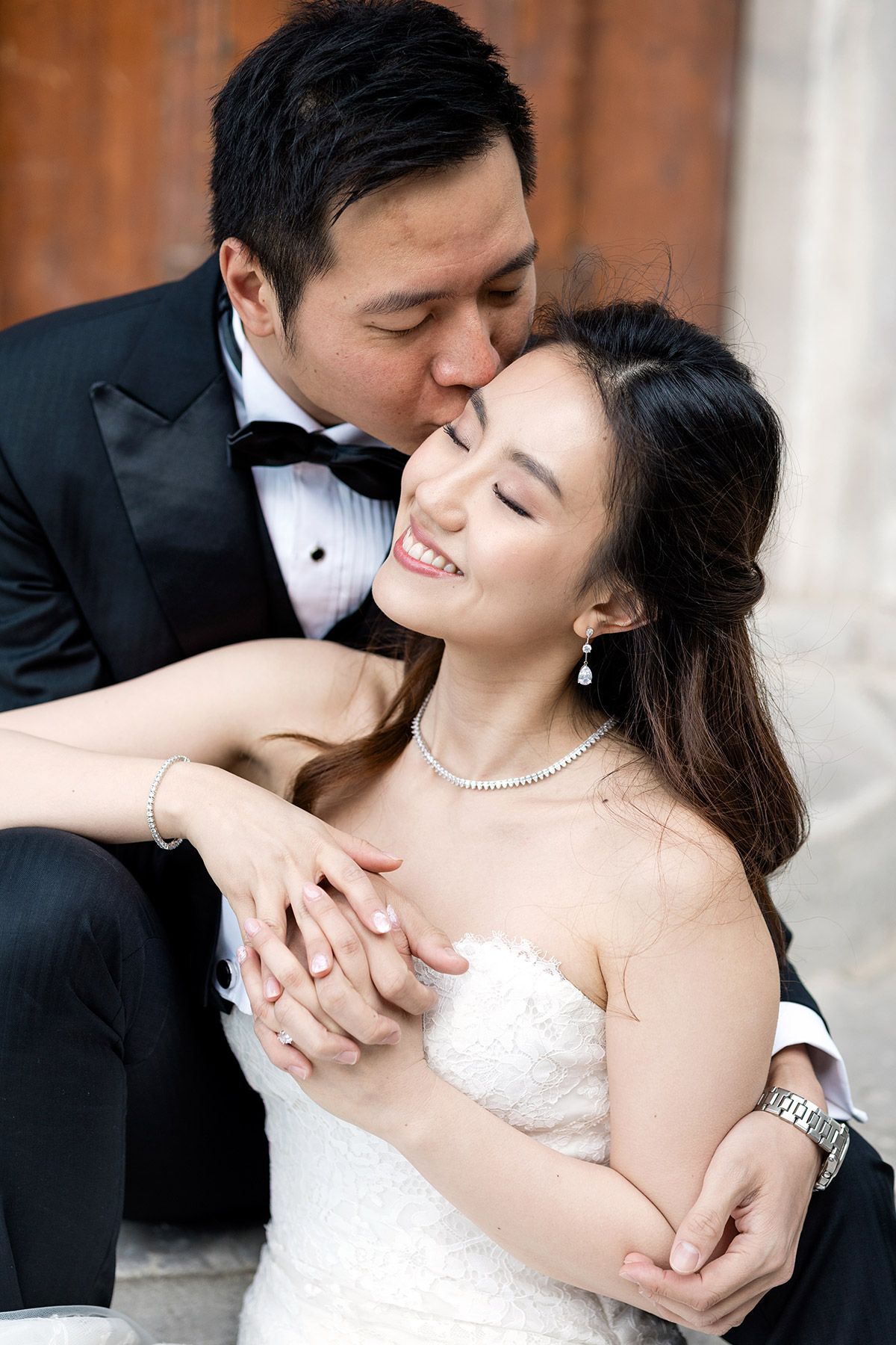 A groom softly kisses his smiling bride on the cheek as she holds his hand during an intimate wedding portrait session in Istanbul.