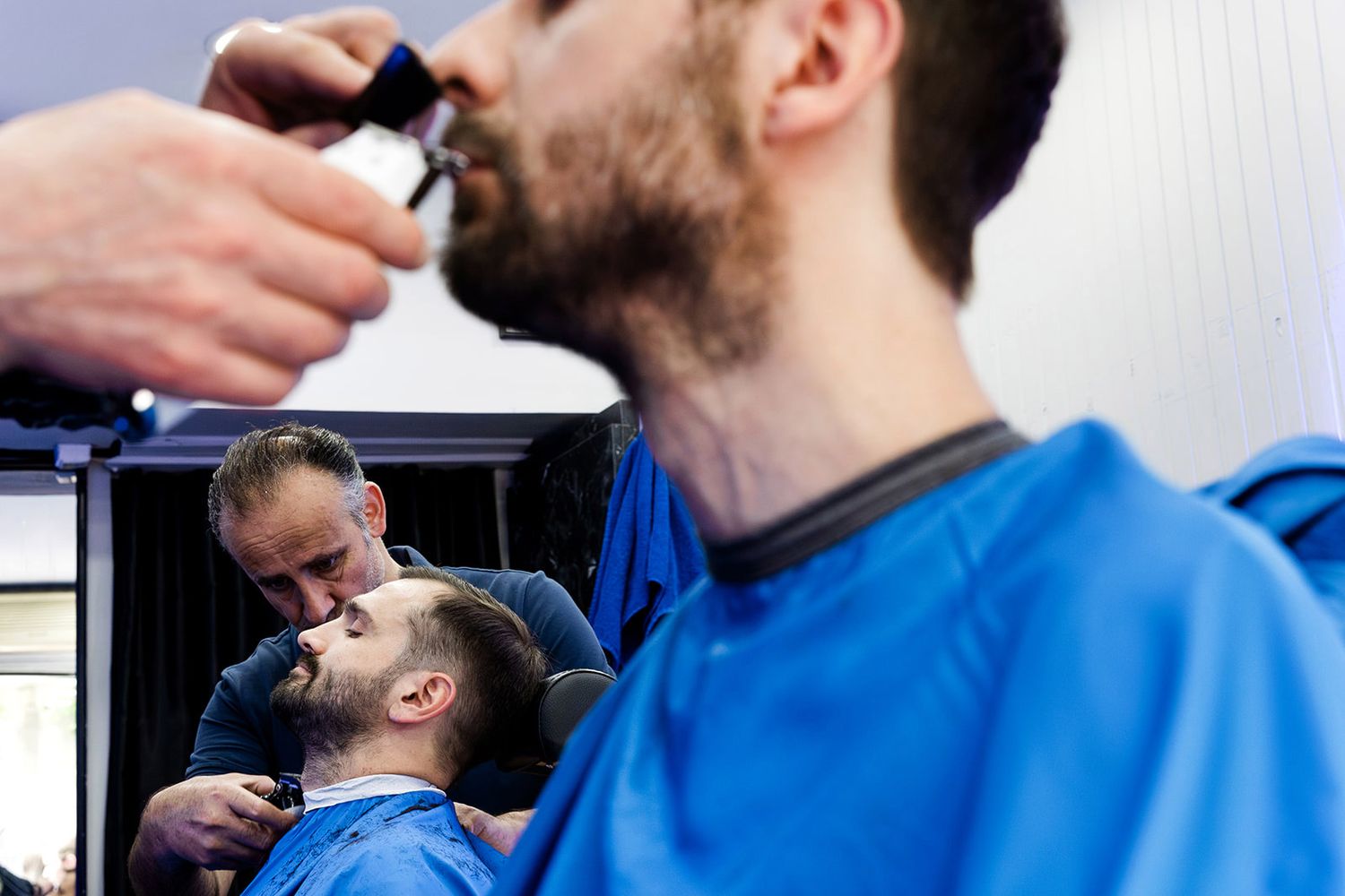 Documentary groom prep photo of a Turkish barber carefully trimming the groom's beard before his wedding at Aslı Tunca in Istanbul.
