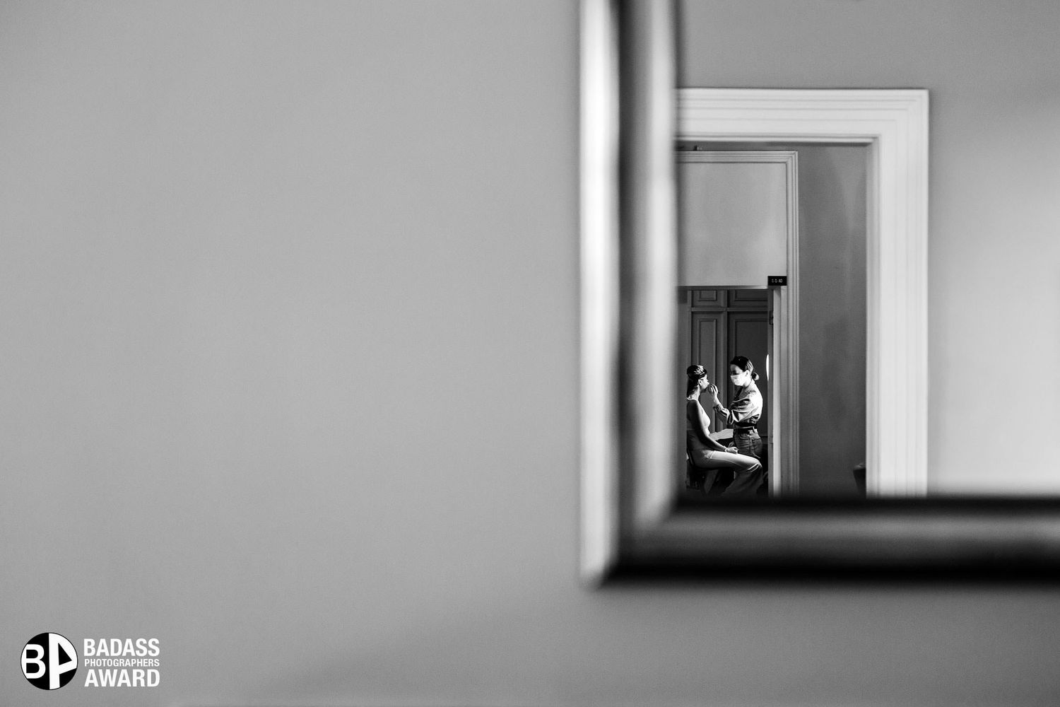 Badass Award-winning black and white documentary photo of a bride getting her makeup done, framed creatively in a mirror.