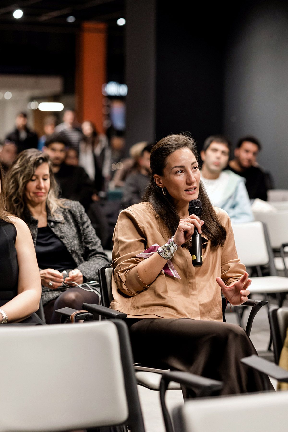 An engaged female attendee using a microphone to participate in an interactive audience Q&A session during a corporate business seminar.