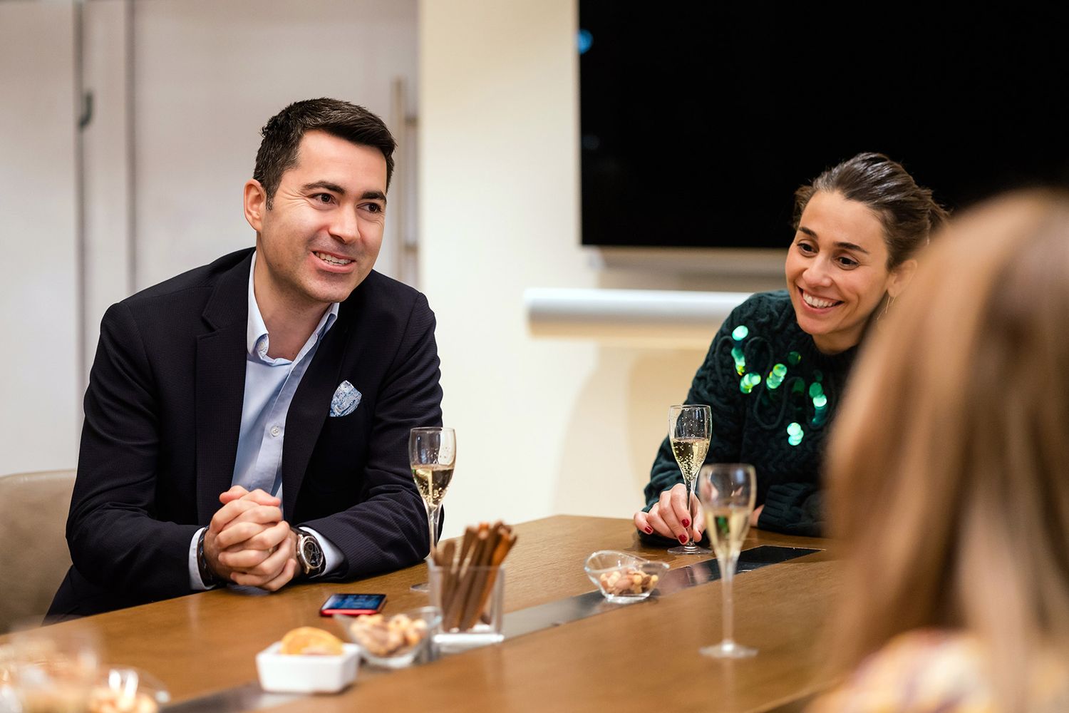 Corporate executives smiling and engaged in conversation over champagne during an intimate VIP networking event.