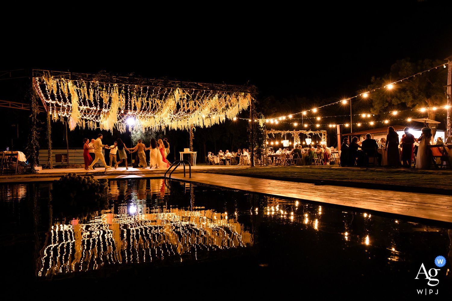 AG WPJA award-winning nighttime wedding reception photo showing guests dancing, beautifully reflected in a dark swimming pool.