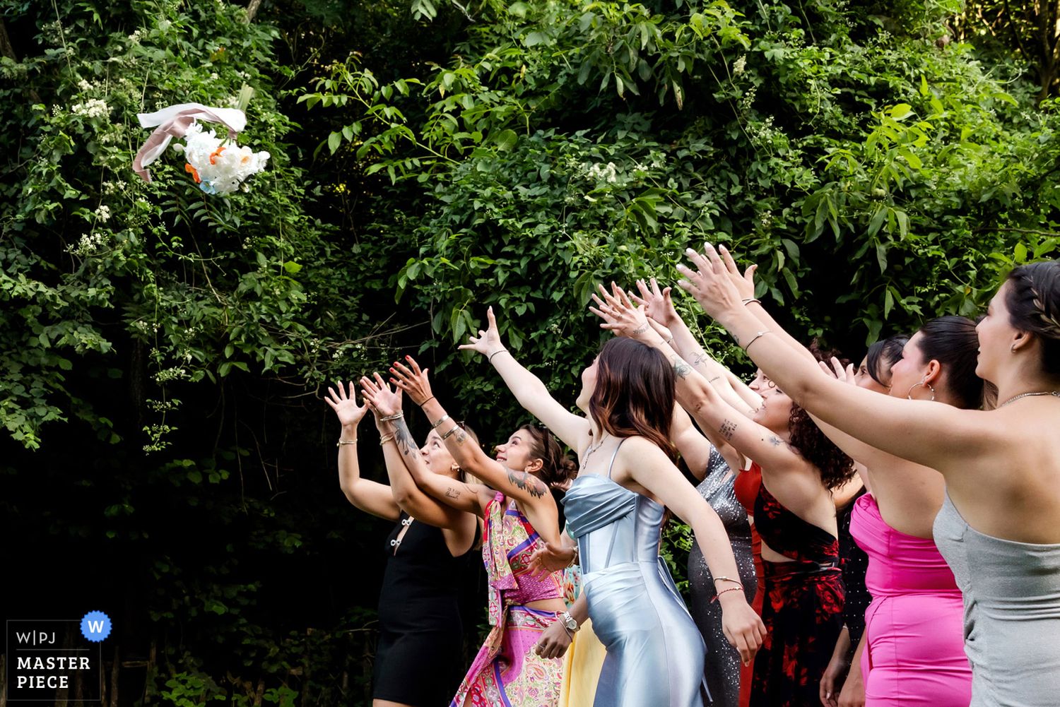 WPJA award-winning action shot capturing a group of excited bridesmaids reaching into the air to catch the bride's flying bouquet.