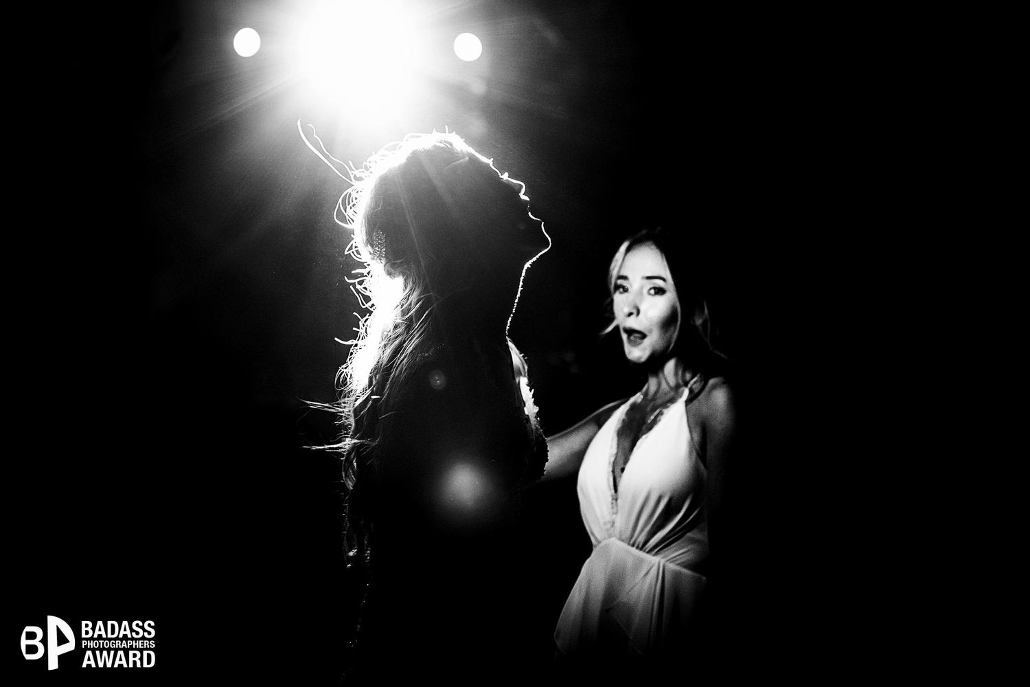 Badass Award-winning candid dance floor photo with dramatic backlighting and a funny, unscripted expression from a wedding guest.