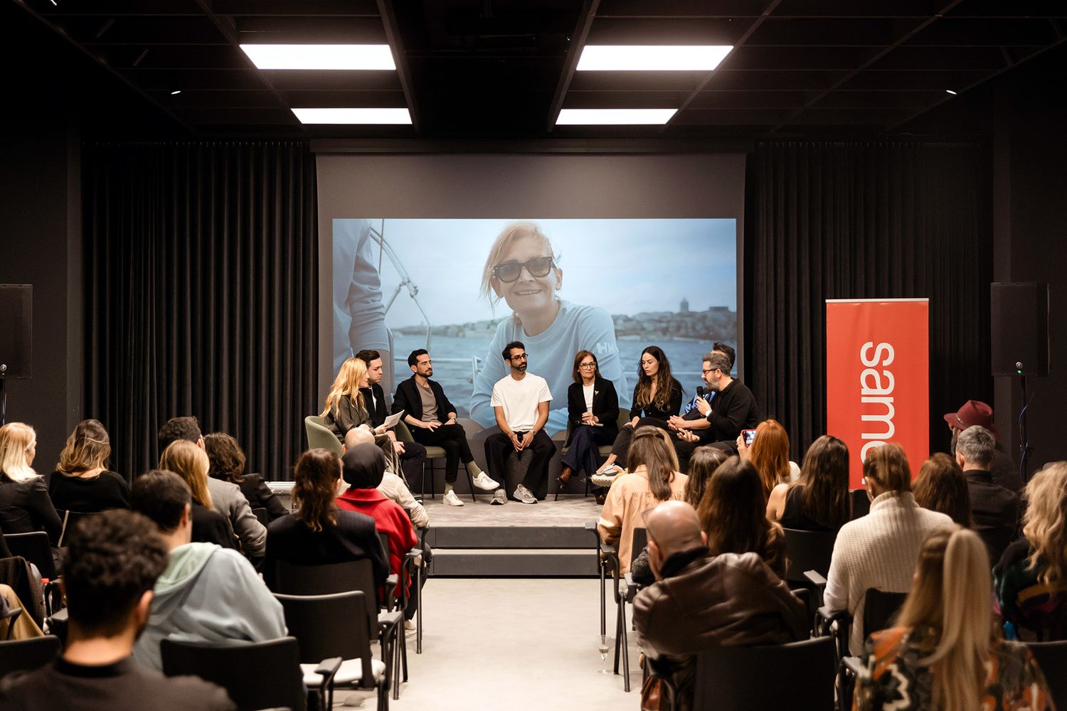 A panel of industry experts speaking on stage in front of an engaged, seated audience at a Samet corporate event in Istanbul.