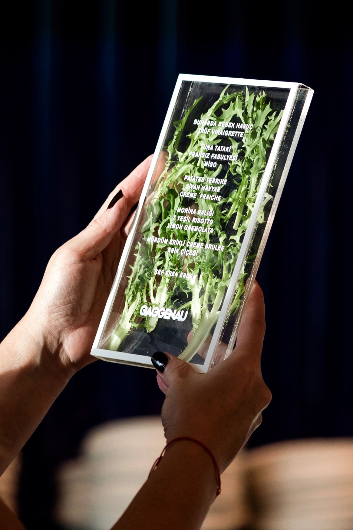 Close-up of a unique transparent acrylic menu designed for an exclusive Gaggenau corporate dining event featuring Chef Eren Erdem.