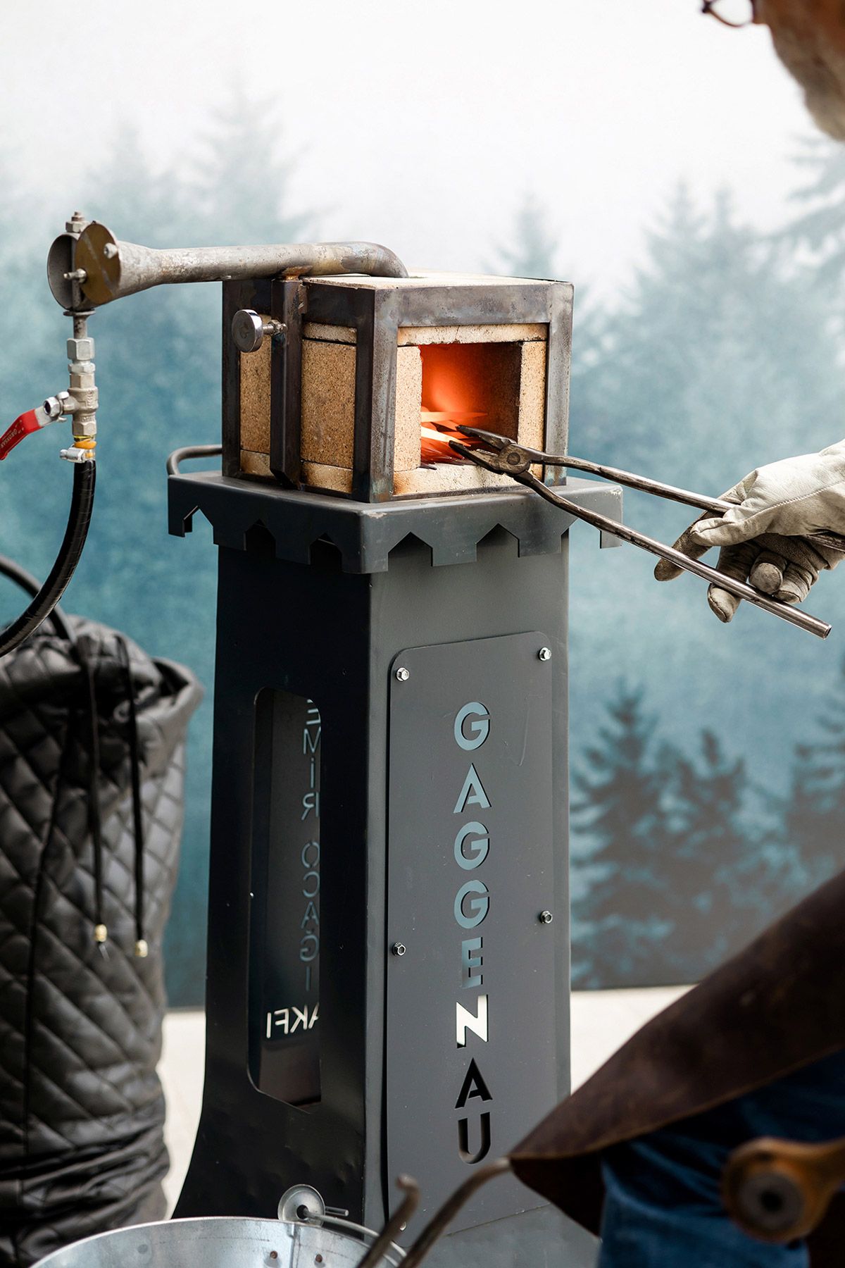 A craftsman demonstrating live metal forging with a custom-branded Gaggenau furnace during a unique luxury brand activation event.