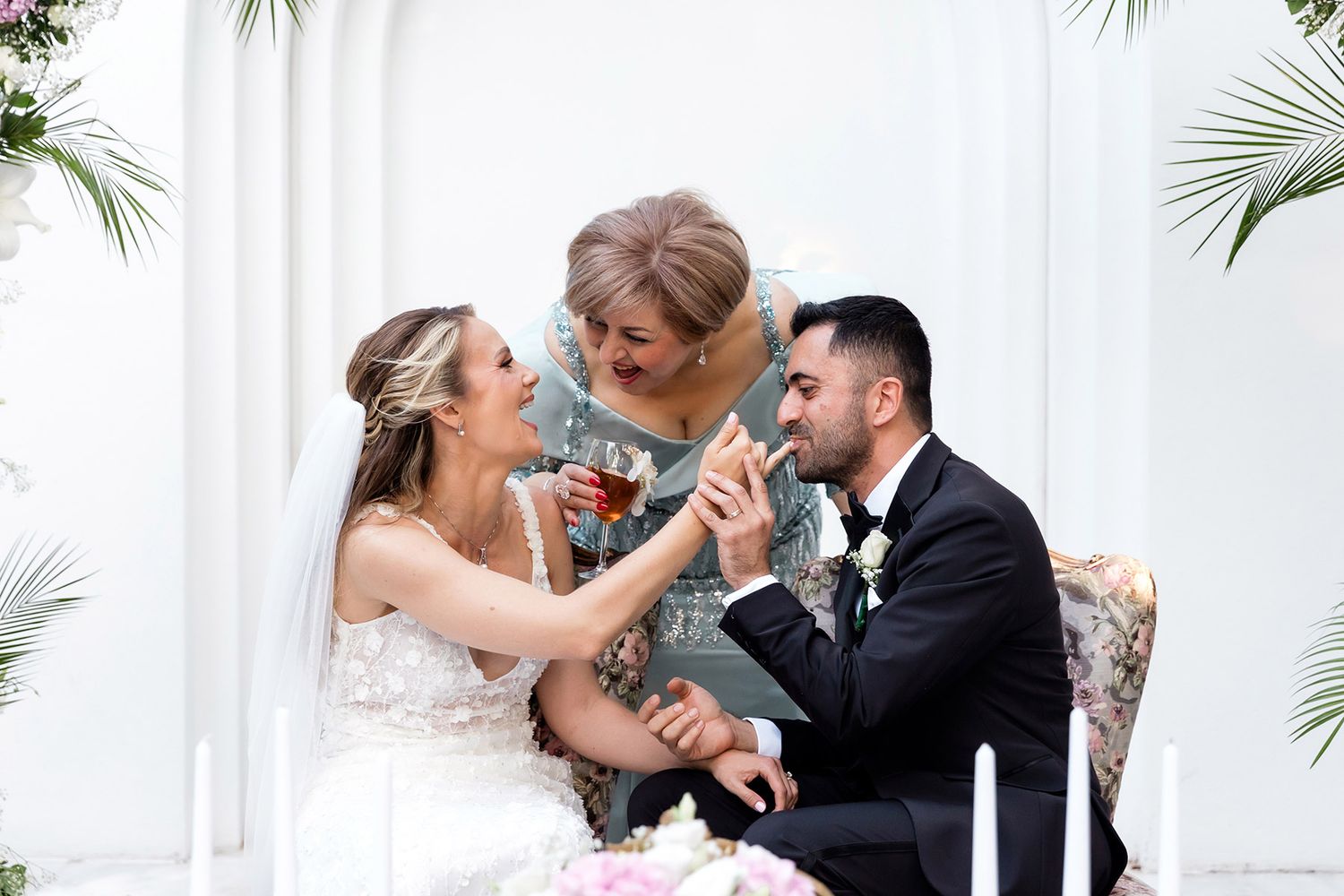 Laughing American bride feeds her Iranian groom honey, a Persian tradition for a sweet marriage, at their Bosphorus Palace wedding.