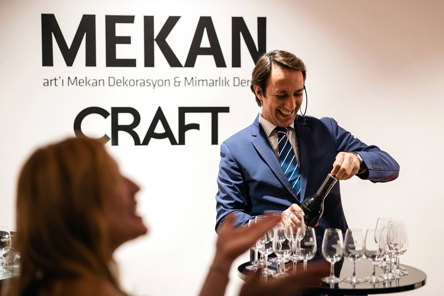 A smiling professional pouring Glenmorangie whiskey during a luxury tasting masterclass at a Mekan Craft brand activation.