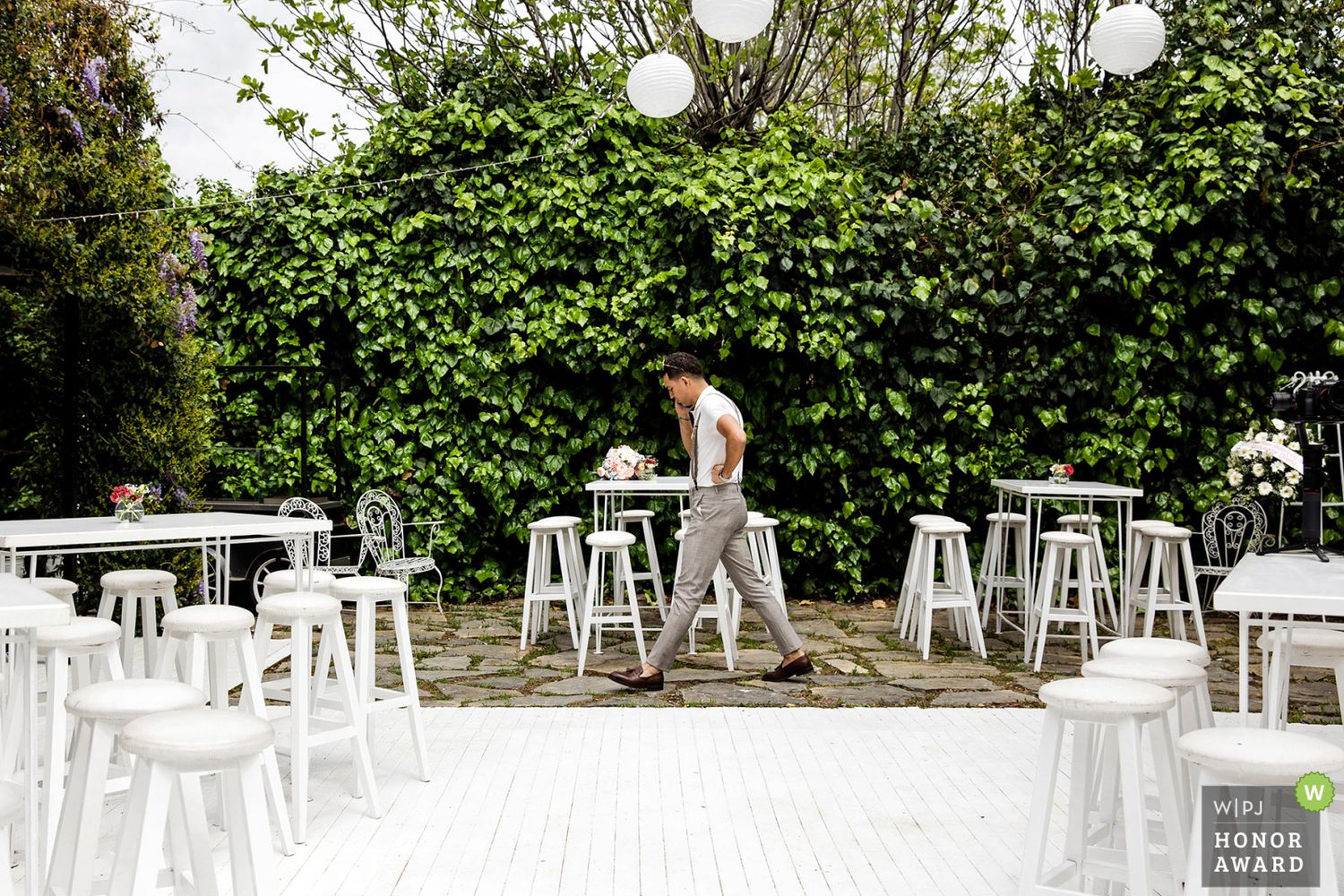 WPJA award-winning documentary shot of a groom pacing alone through a beautiful outdoor wedding reception setup before the guests arrive.