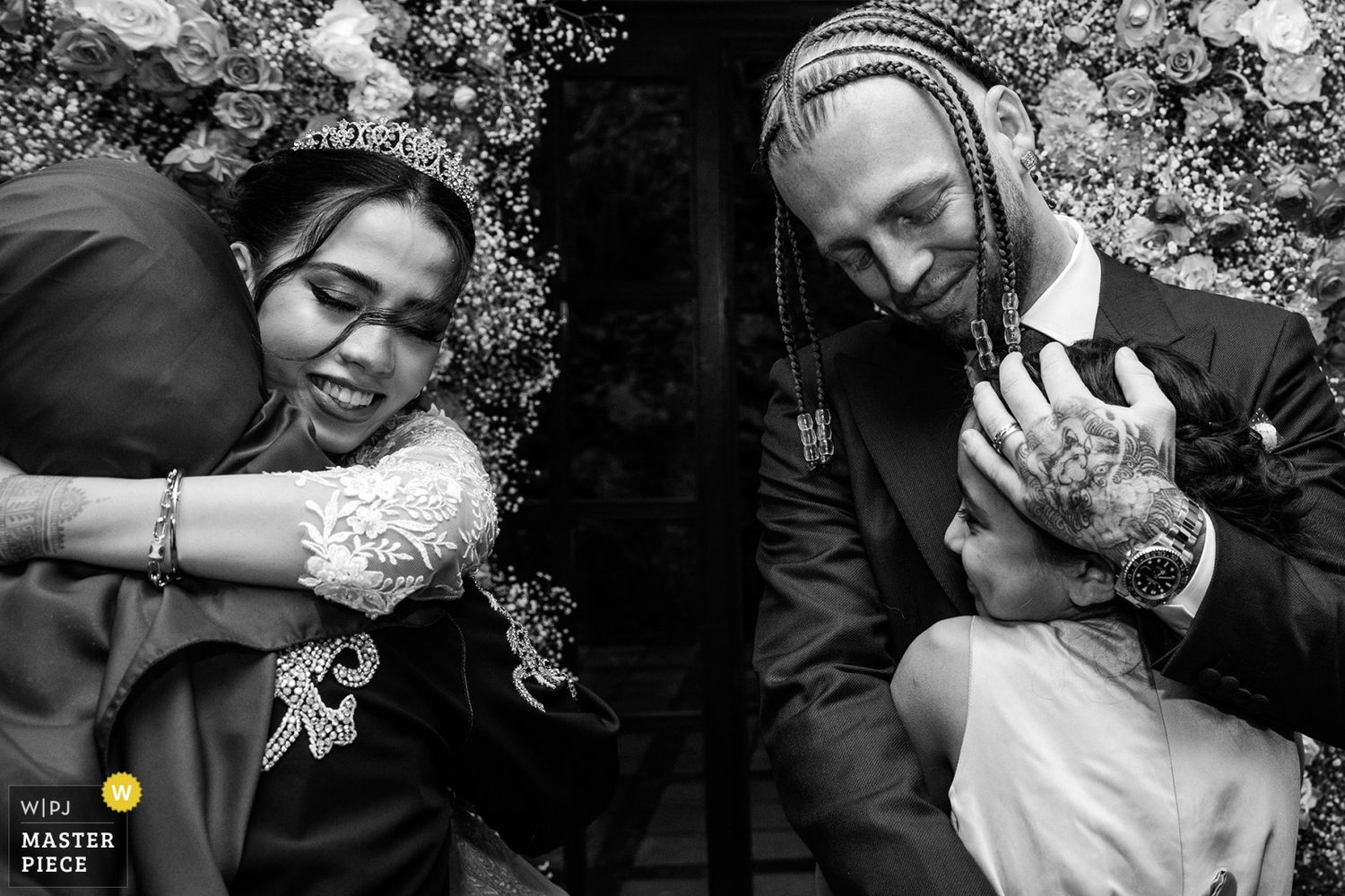 WPJA award-winning black and white photo capturing a deeply emotional moment as a bride and groom warmly hug their family members.