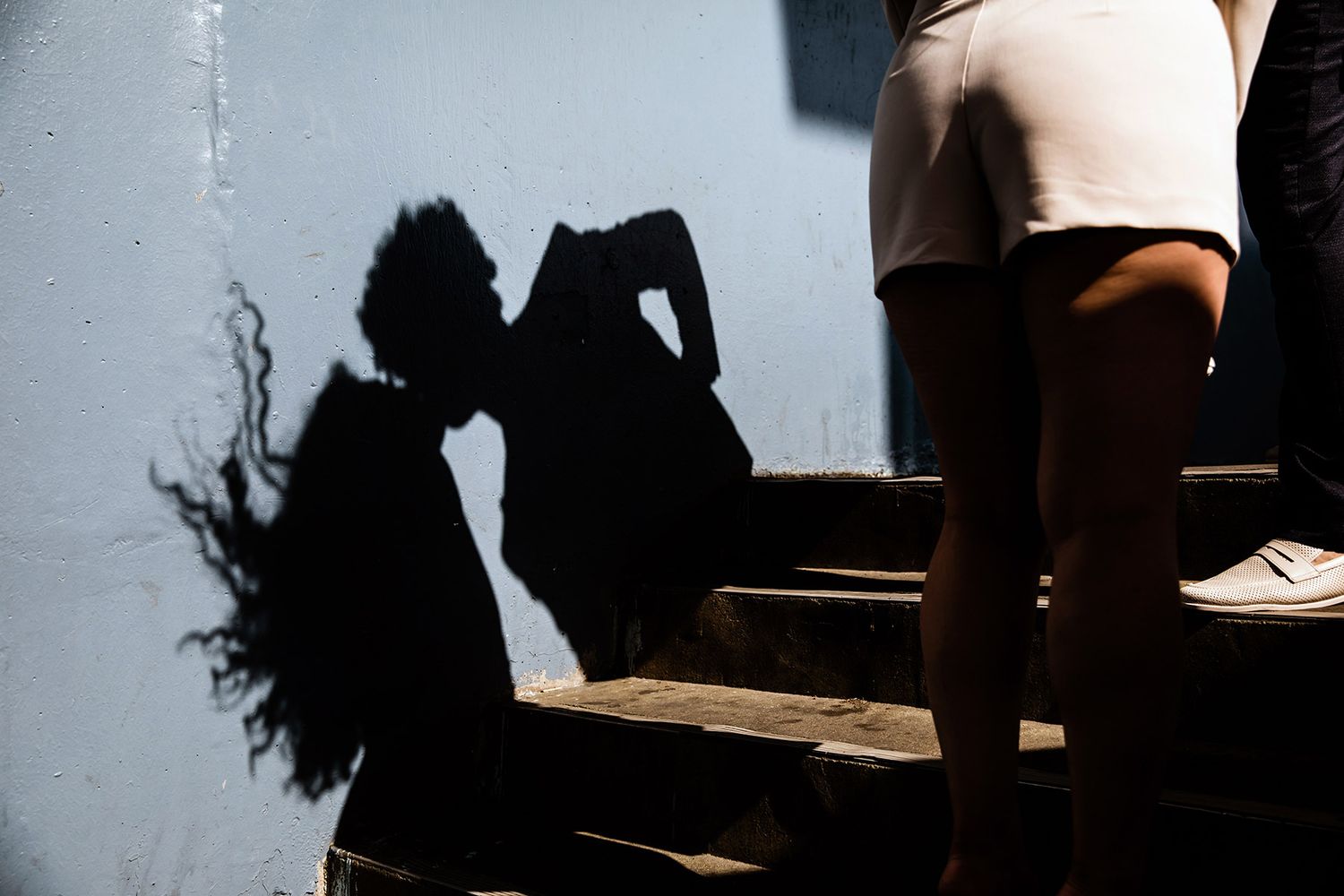 Creative documentary photography showing the hard, dramatic shadow of a couple kissing, with the woman's hair blowing in the wind, Istanbul.